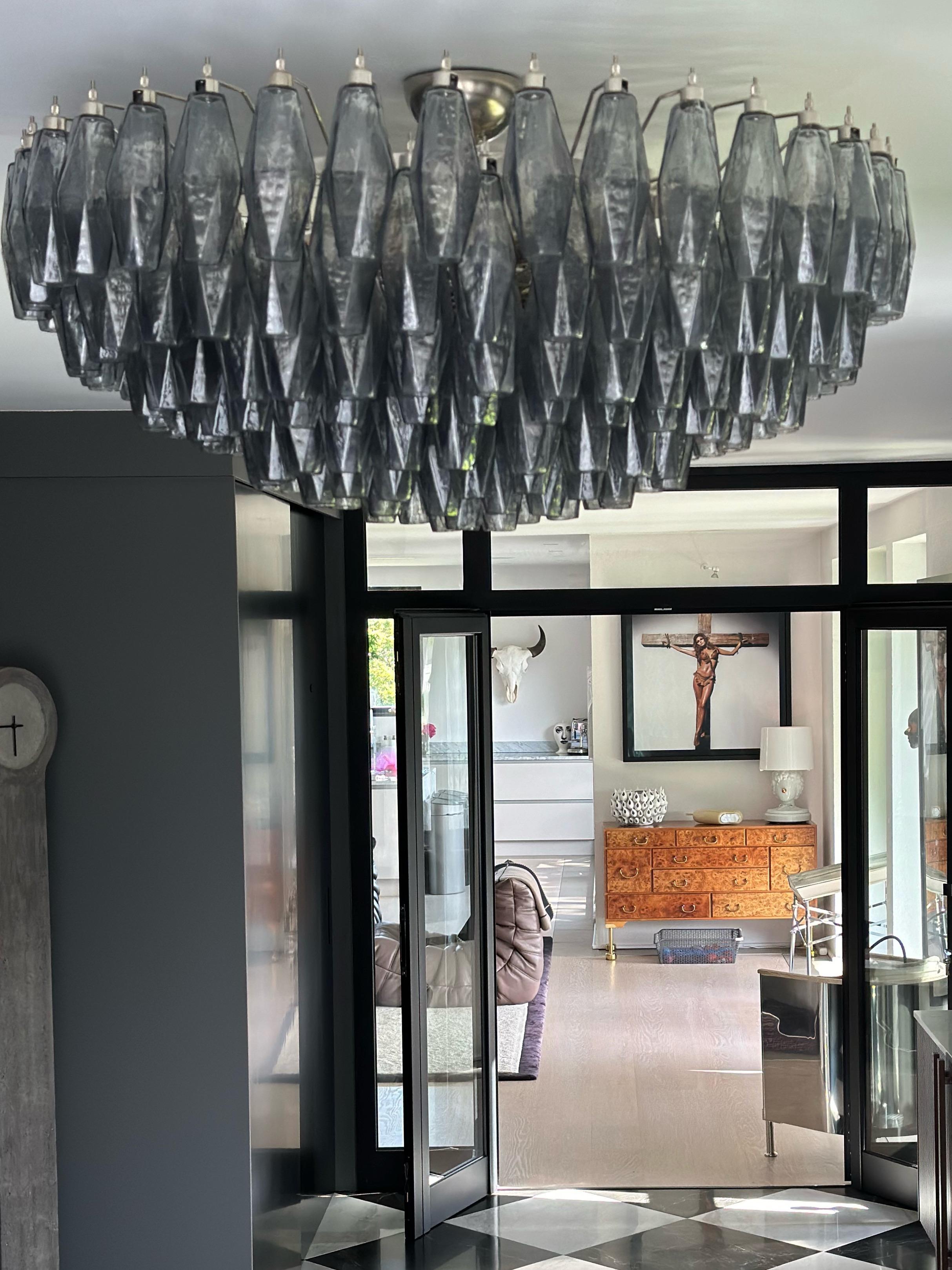 Coppia di grandi lampadari di Murano in stile Carlo Scarpa. Bellissimi prismi poliedrici soffiati a mano in una tonalità di grigio fumé, che con una certa luce e senza le luci accese sembrano quasi neri.
Struttura della lampada in cromo.
I lampadari