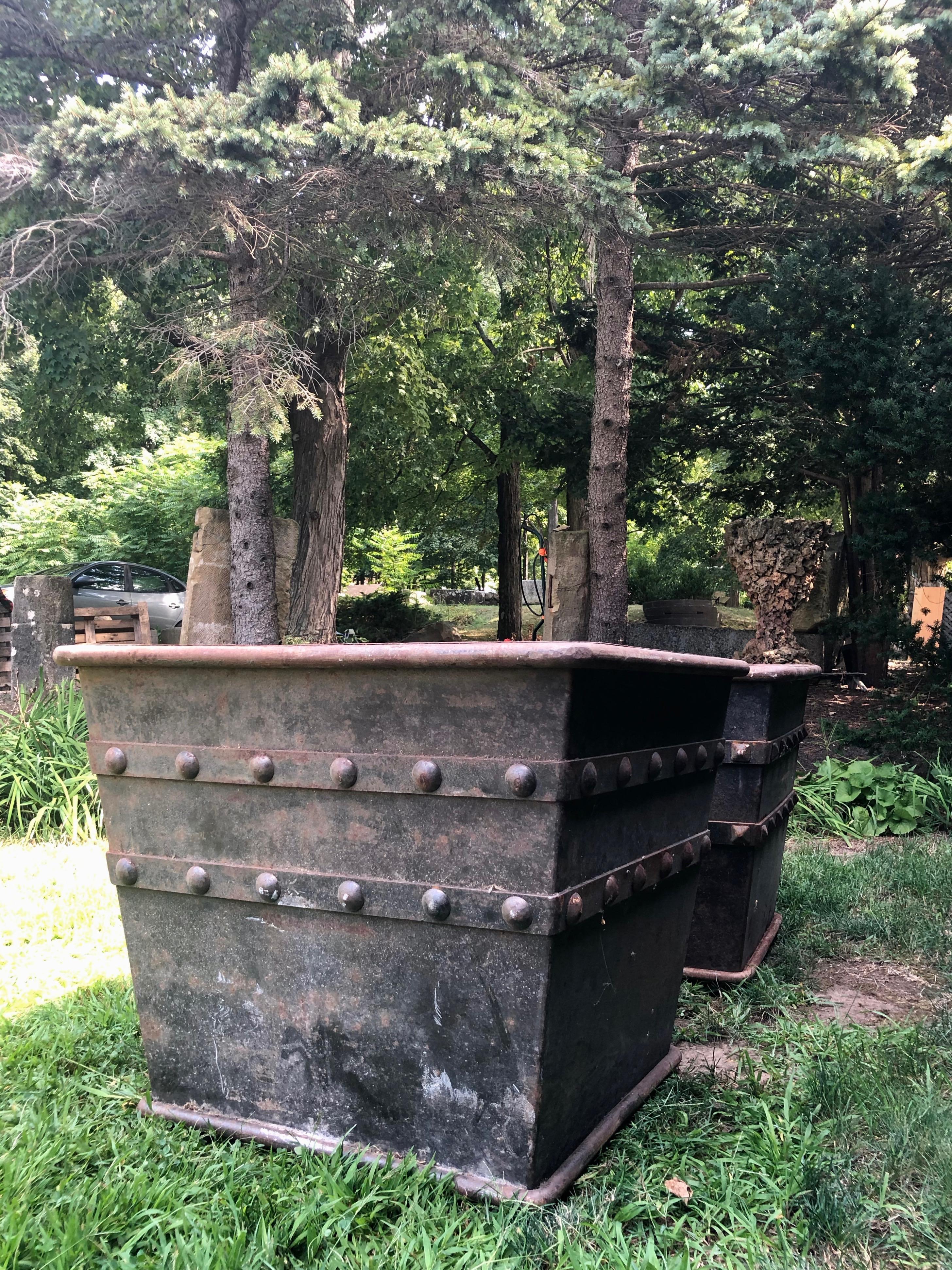 What a find! This pair of huge iron/steel planters feature enormous planting wells and studded decoration. Not an exact pair, as one has round studs, while the other has diamond-shaped studs. No matter, as both are in exceptional condition with a