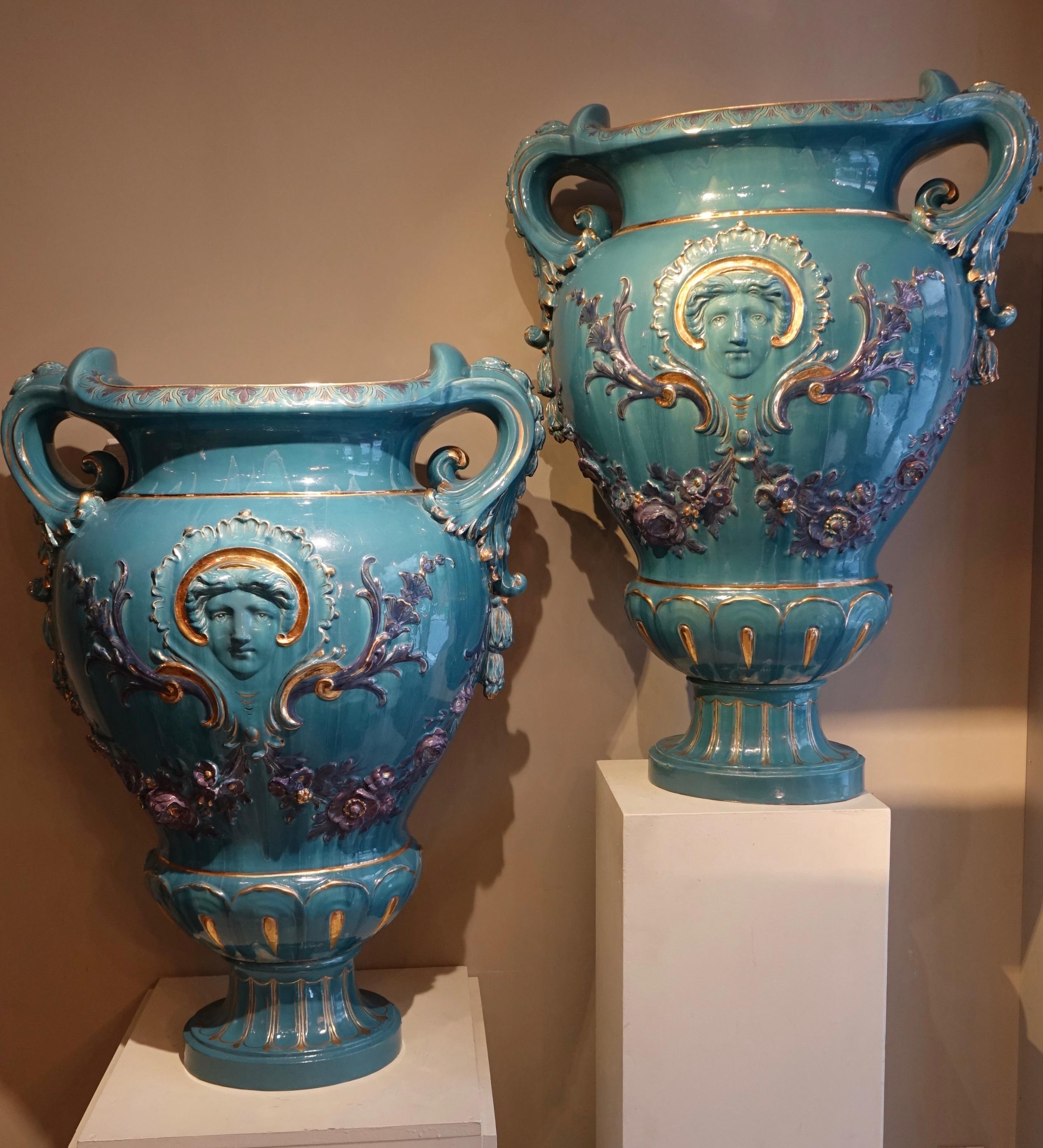 Pair of large Medicis vases in blue-green earthenware with acanthus leaf-shaped handles.
Decorated on the four sides, mascarons surrounded by foliage scrolls and purple flower garlands. The whole is highlighted with gilding giving more depth to the