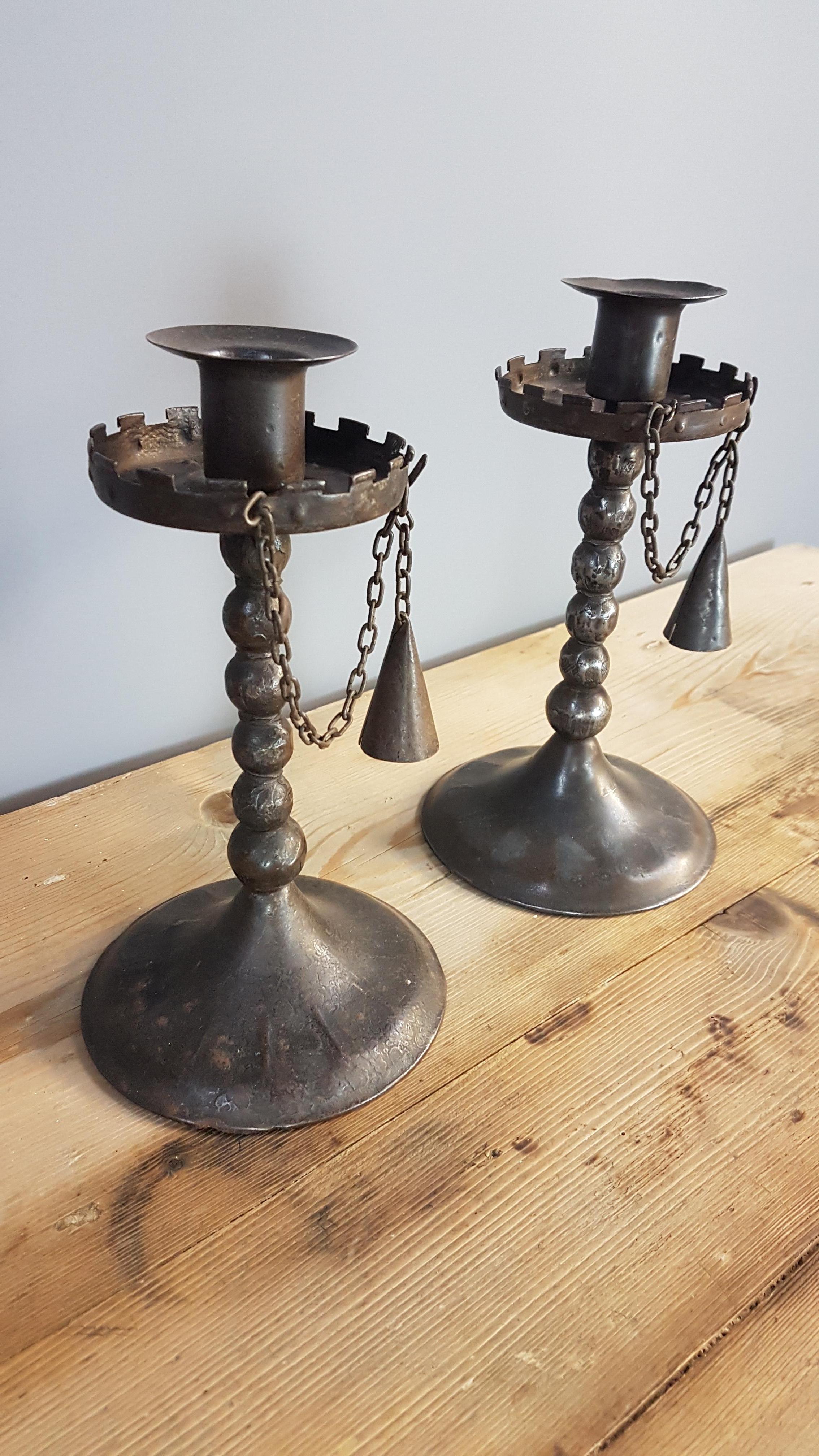 A superb and rare pair of Hugo bergère 'Goberg' arts and crafts candle stands with their original chains and candle snuffers. These have a Lump metal style with castellated formed tops. Measures 12cm diameter at the base and a height of 21cm
