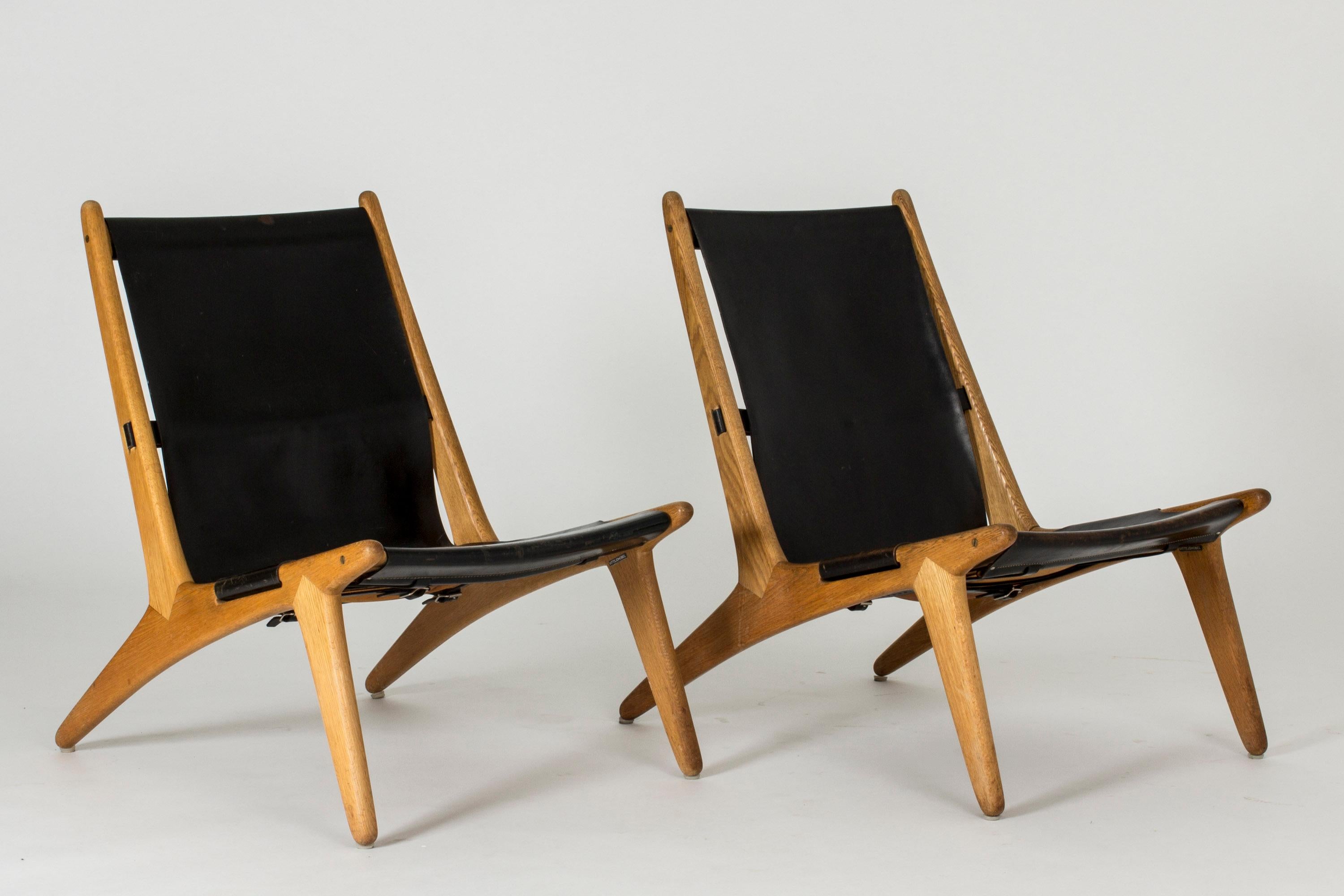 Pair of hunting chairs by Uno & Östen Kristiansson, made in solid teak with leather seats. Casually elegant silhouettes, beautiful joinery, nicely aged leather.
