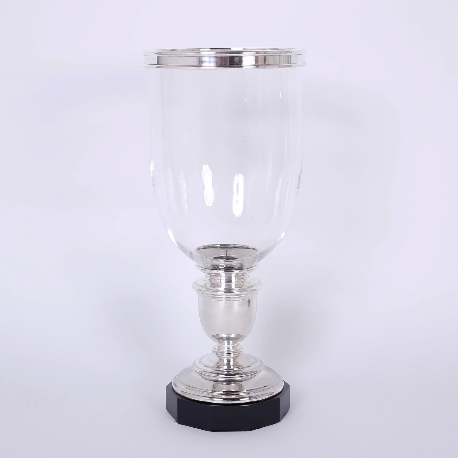 Pair of hurricane candleholders with a bold, large-scale and removable silver plated rim on handblown glass shades. The silver plated bases have a classical form and sit on ebonized, octagon wood stands. Signed Ralph Lauren on a metal plaque.