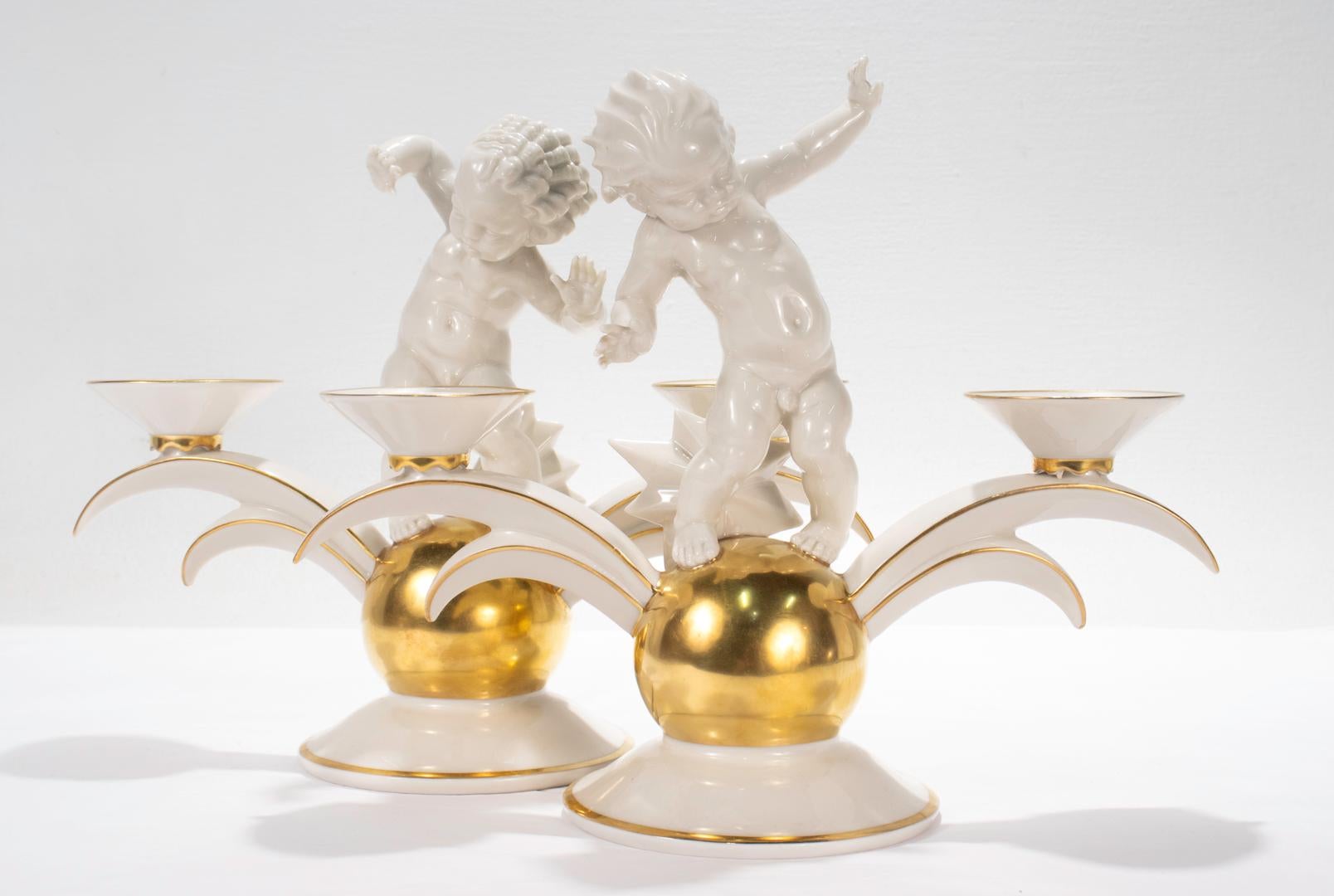A fine pair of German Art Deco porcelain candelabra.

By the Kunstabteilung (Art Department) of the Hutschenreuther Porcelain Manufactory.

Designed by Karl Tutter.

Each depicting a putto or cherub standing on a golden sphere between the two arms