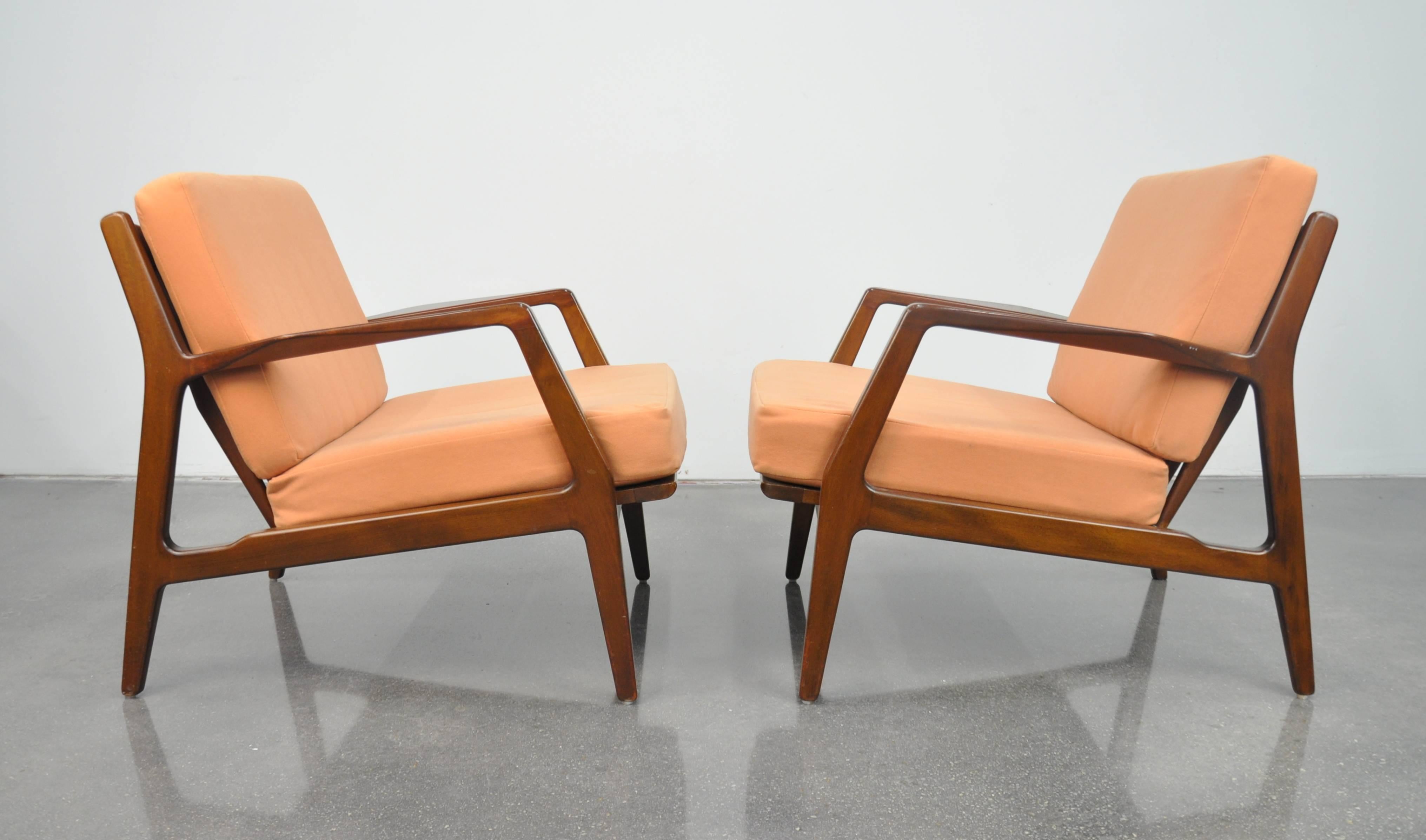 A pair of vintage Danish Modern Mid-Century easy chairs, designed by Ib Kofod Larsen for Selig, dating from the 1960s. The slatted back armchairs have sculptural lines that make them stunning from all angles. The removable cushions are covered in a