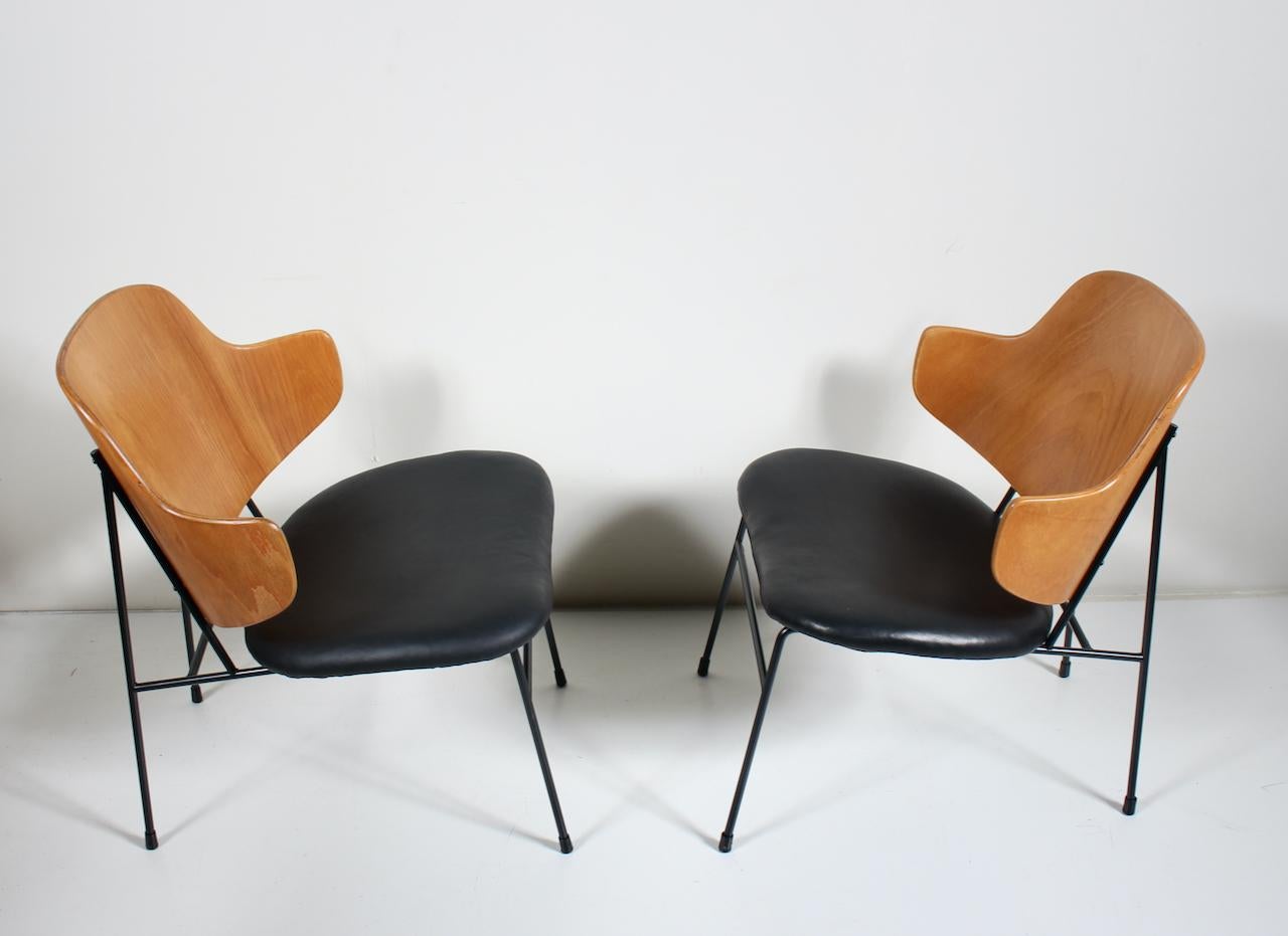 Pair of Danish Modern Kofod-Larsen for Selig Black Leather Penguin Chairs.  Featuring a sturdy black wrought Iron framework with capped feet, slightly slanted, curved and steamed laminated wood seat back with newly upholstered black leather