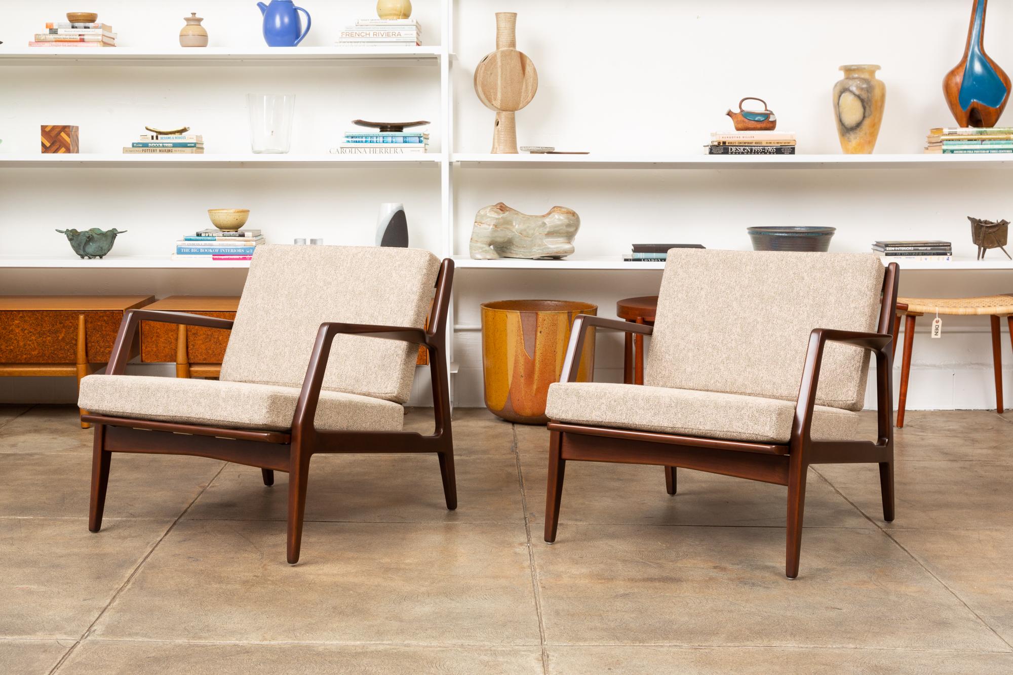 Pair of Model 41 easy chairs by Ib Kofod-Larsen for Magnus Olsen, Denmark c.1950. These chairs were imported for the American market by Selig. The body is constructed of stained beech, with sculpted arms and a slatted back. The cushions are newly