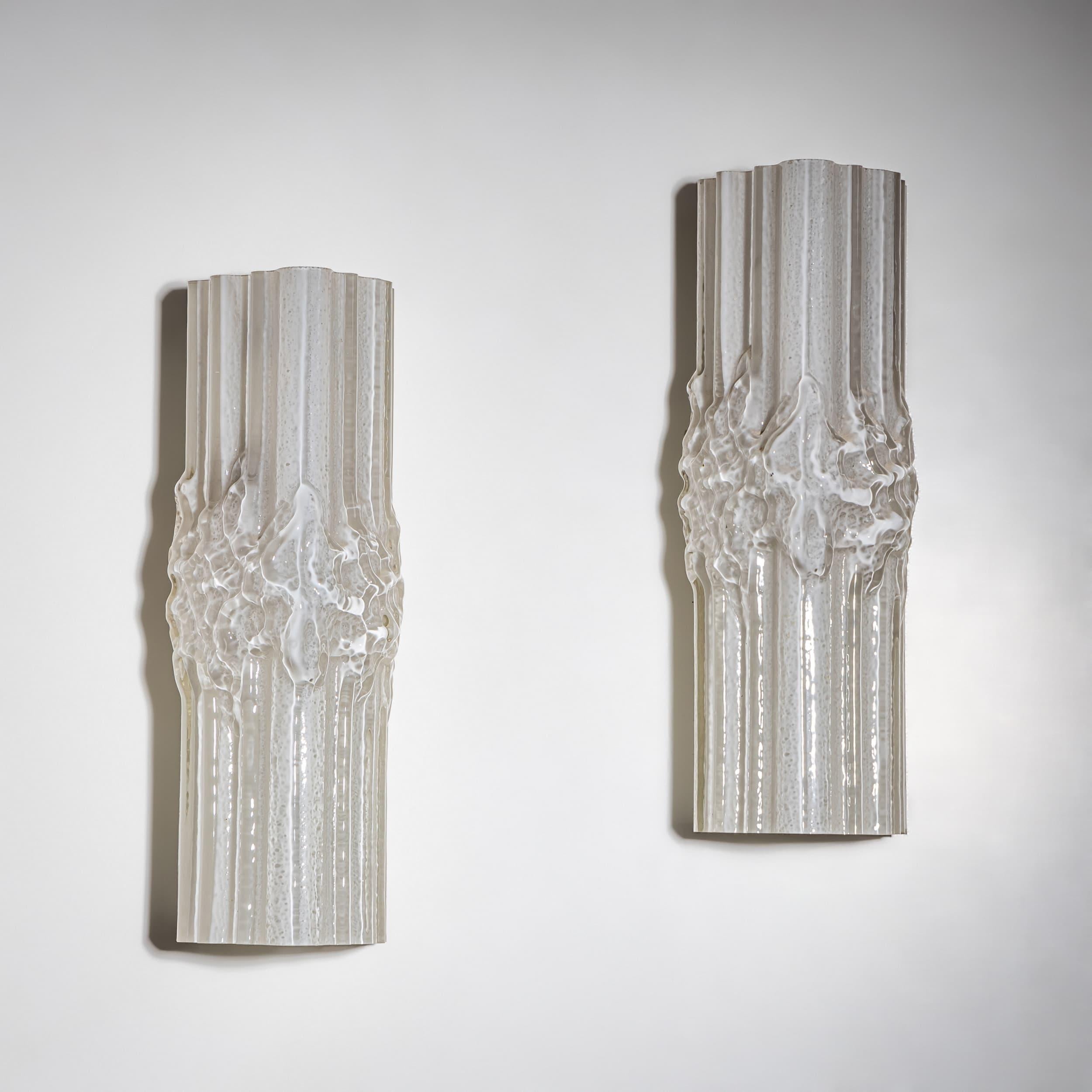 Pareja de apliques de cristal de Murano blanco esmerilado con textura irregular en la superficie. Fijación trasera de metal lacado en blanco.