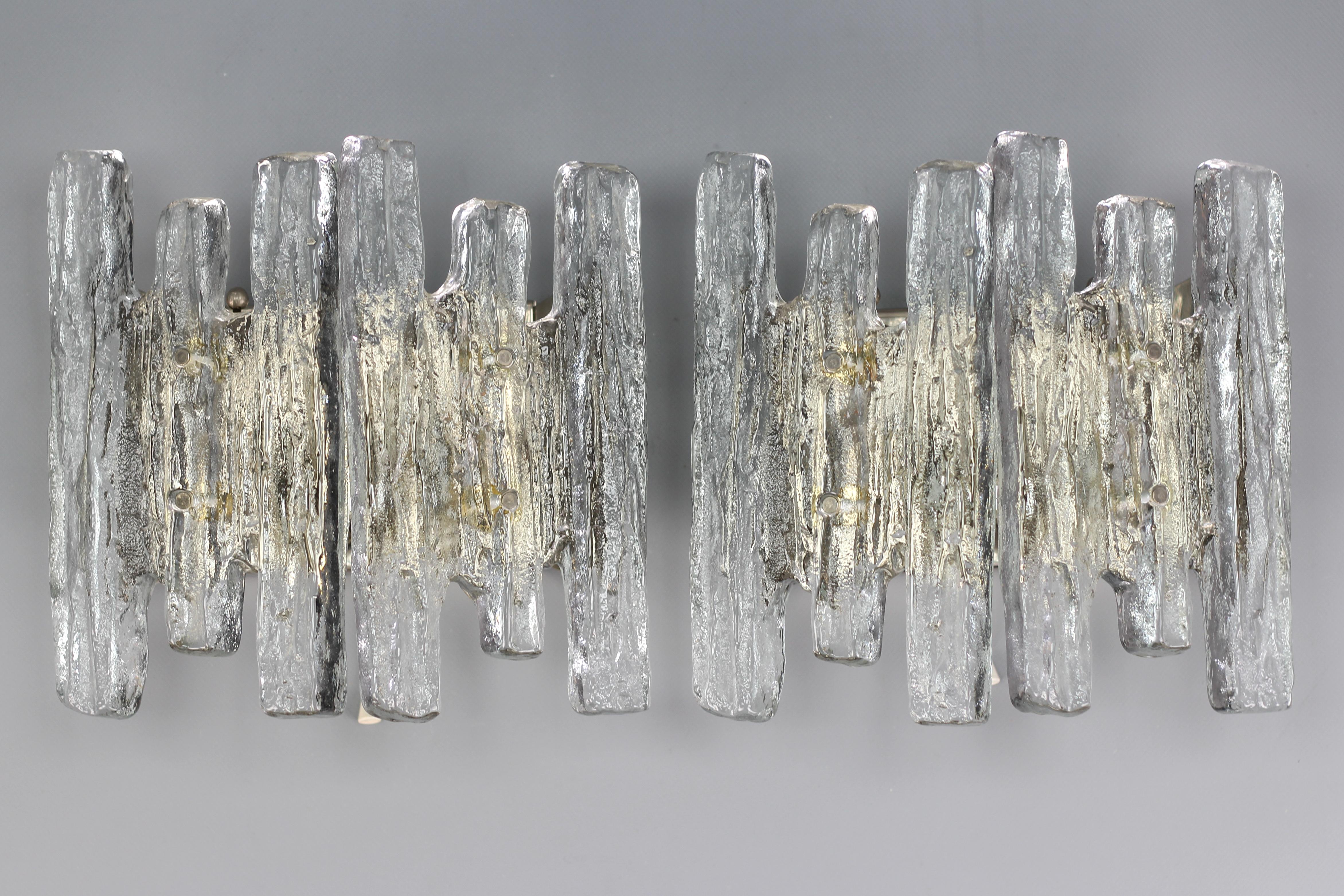 An impressive pair of Mid-Century Modern icicle ice glass wall sconces made by Kalmar, Franken KG, Austria, circa in the 1970s.
Beautiful and elegant design wall sconces, each having two heavy blocks of ice glass, nickel-plated steel backplate with