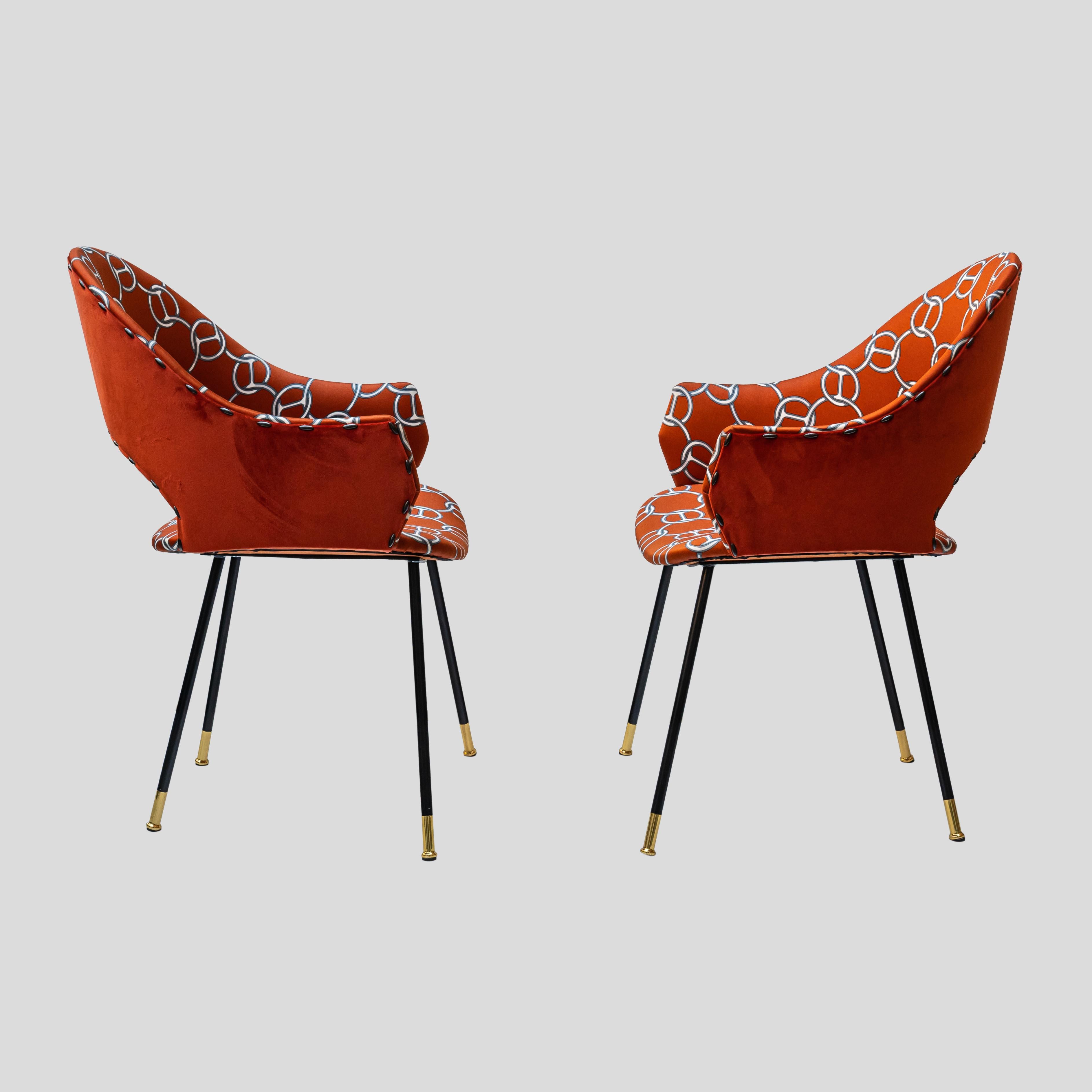 Paire de chaises à dossier rond. Quatre pieds allongés et inclinés en fer émaillé noir, terminés par une pointe en métal laitonné. La coque de l'assise, fabriquée en contreplaqué, est généreusement paddée de mousse de polyuréthane et ornée d'un