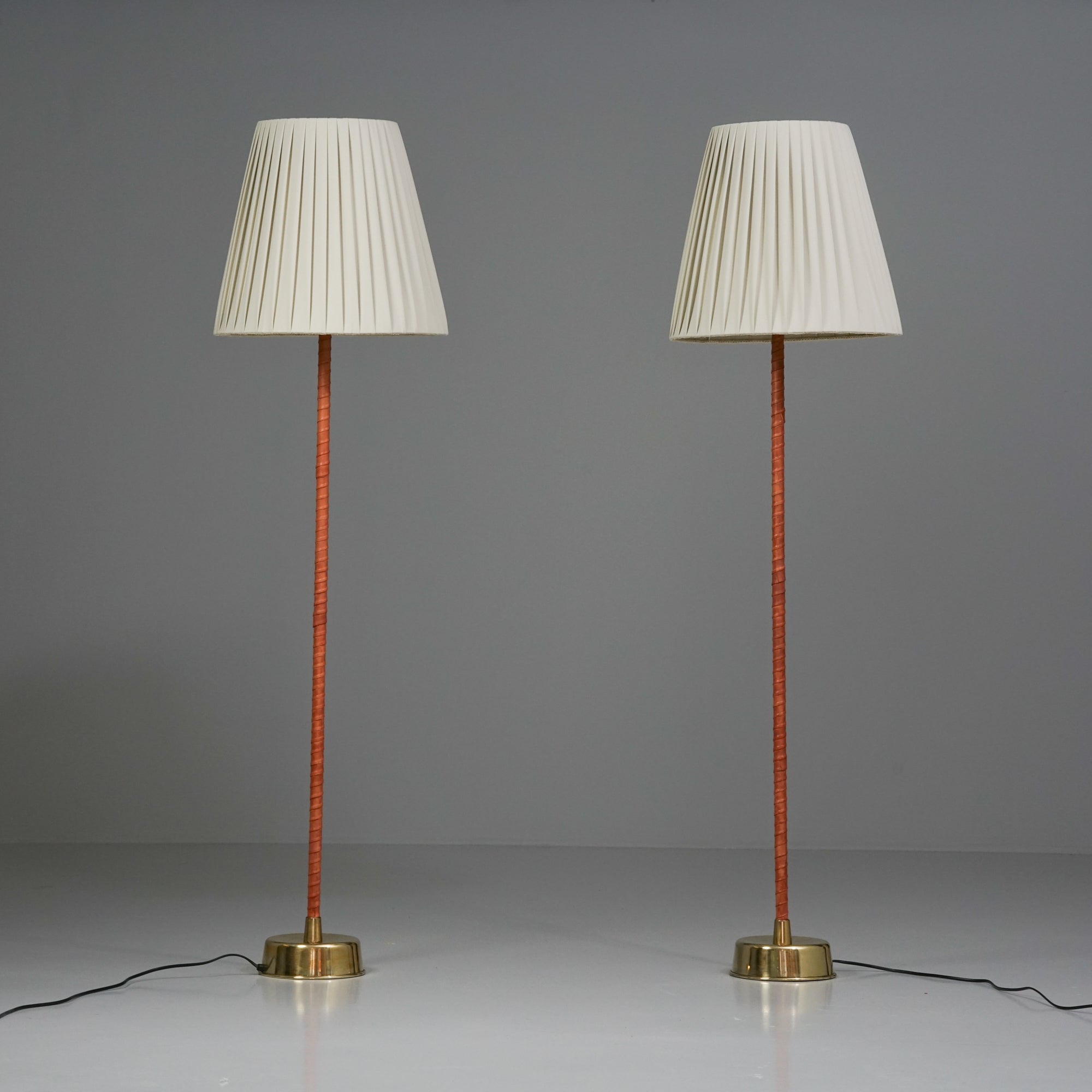 Coppia di lampade da terra Ihanne/Senator, design di Lisa Johansson-Pape, prodotte da Orno Oy, anni '50. Rivestimento in pelle della struttura, ottone, nuovi paralumi in tessuto fatti a mano. Buone condizioni vintage, lieve patina coerente con l'età