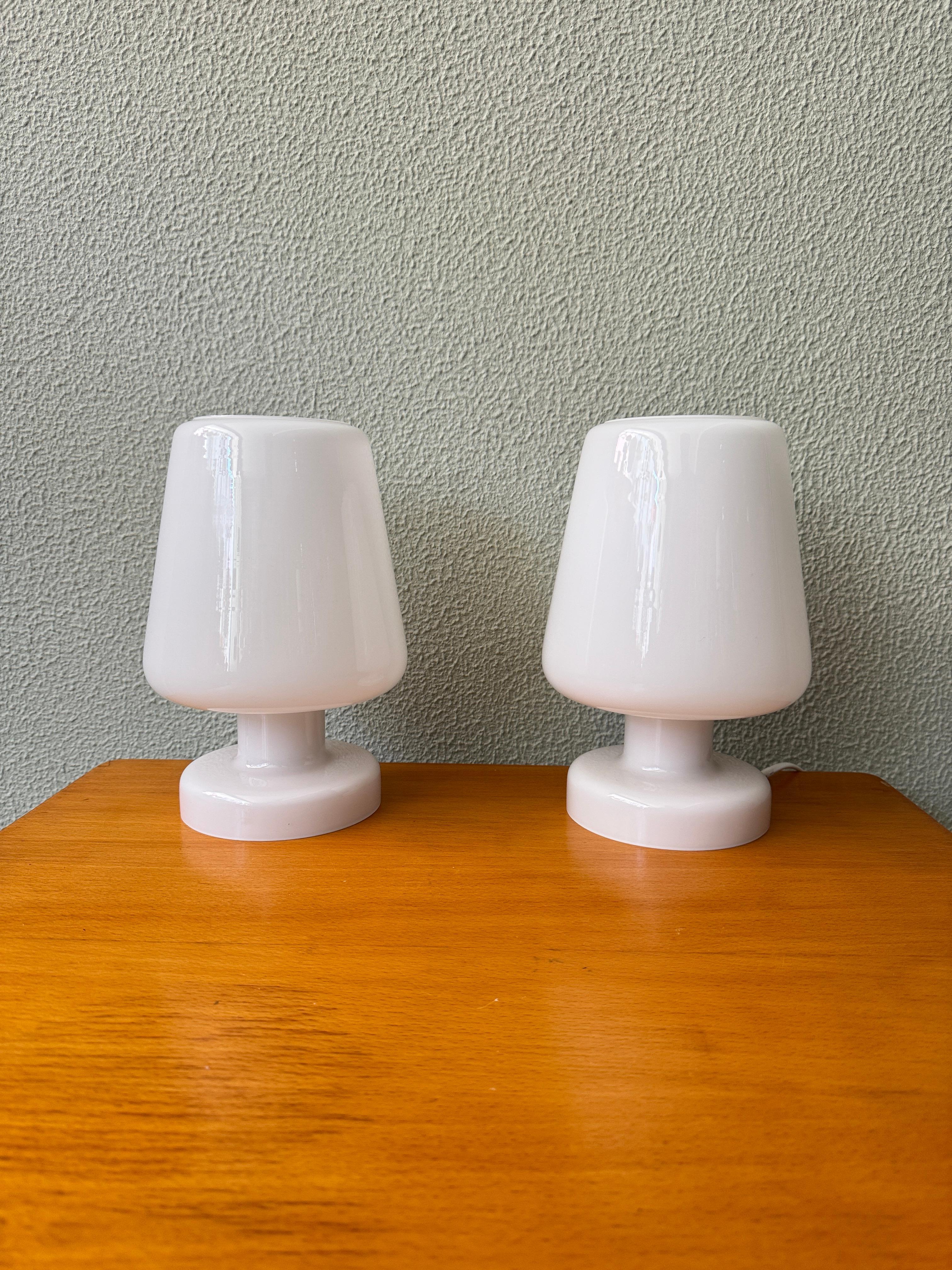 Cette paire de lampes de table GULDLÖK d'Ikea (Suède) illustre l'éthique du design scandinave minimaliste de la marque. 

Entièrement fabriquée en verre opalin blanc, chaque lampe fusionne la base et l'abat-jour en une forme sculpturale homogène.