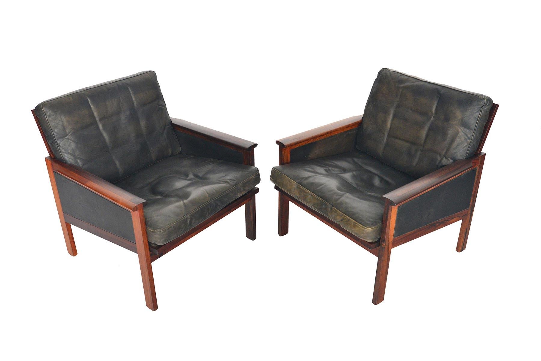 This pair of Danish modern lounge chairs was designed by Illum Wikkelsø as the ‘Capella’ model for N. Eilersen in 1959. Framed in solid rosewood, this chair features a beautifully crafted finger joint on the armrest. Leather panels rest beneath the