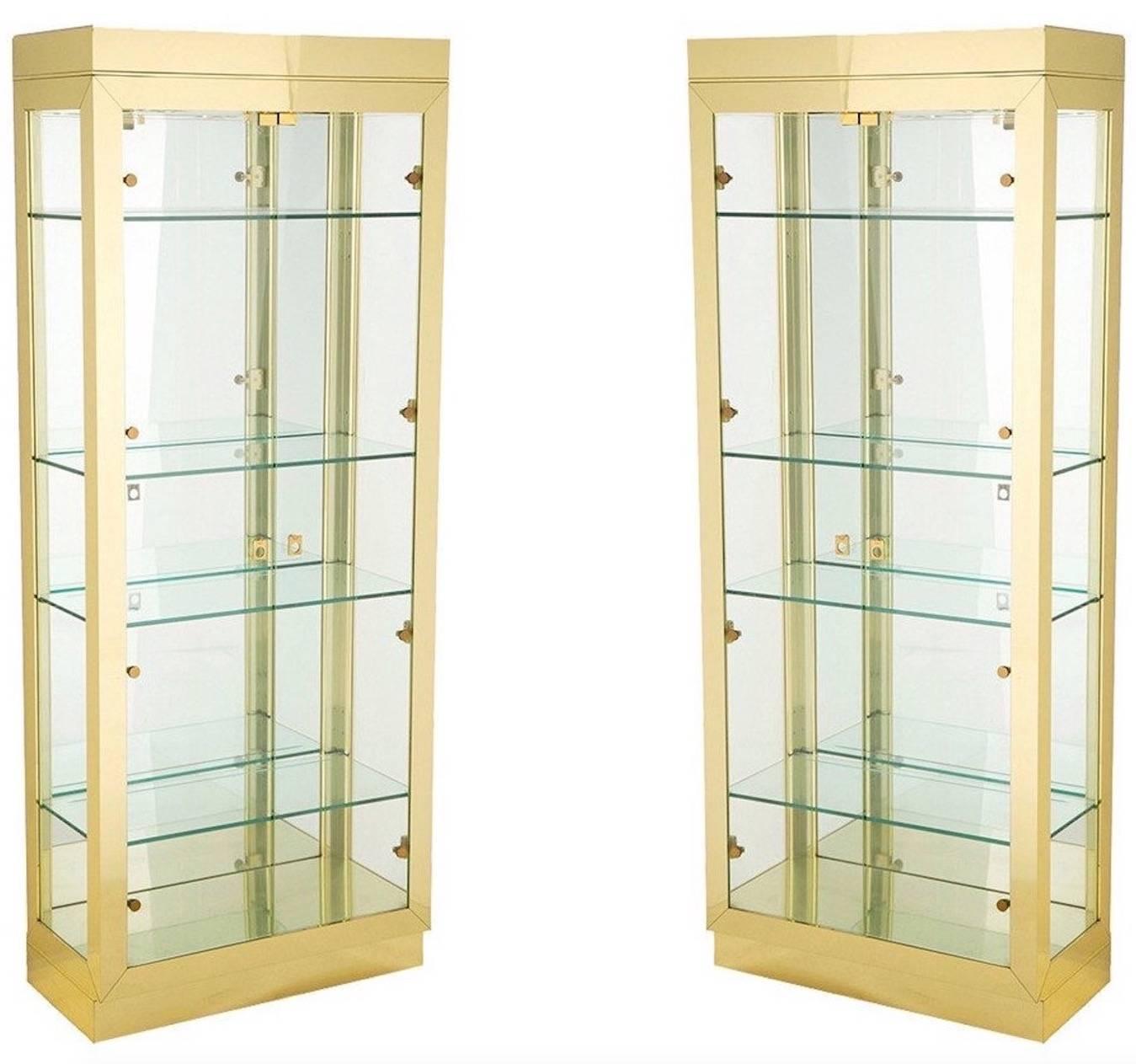 Pair of polished brass, glass and mirror illuminated vitrine display cases each with two double glass doors, four adjustable glass shelves with groove for standing plates and two spotlights in the ceiling with a dimmer switch. Glass sides and mirror