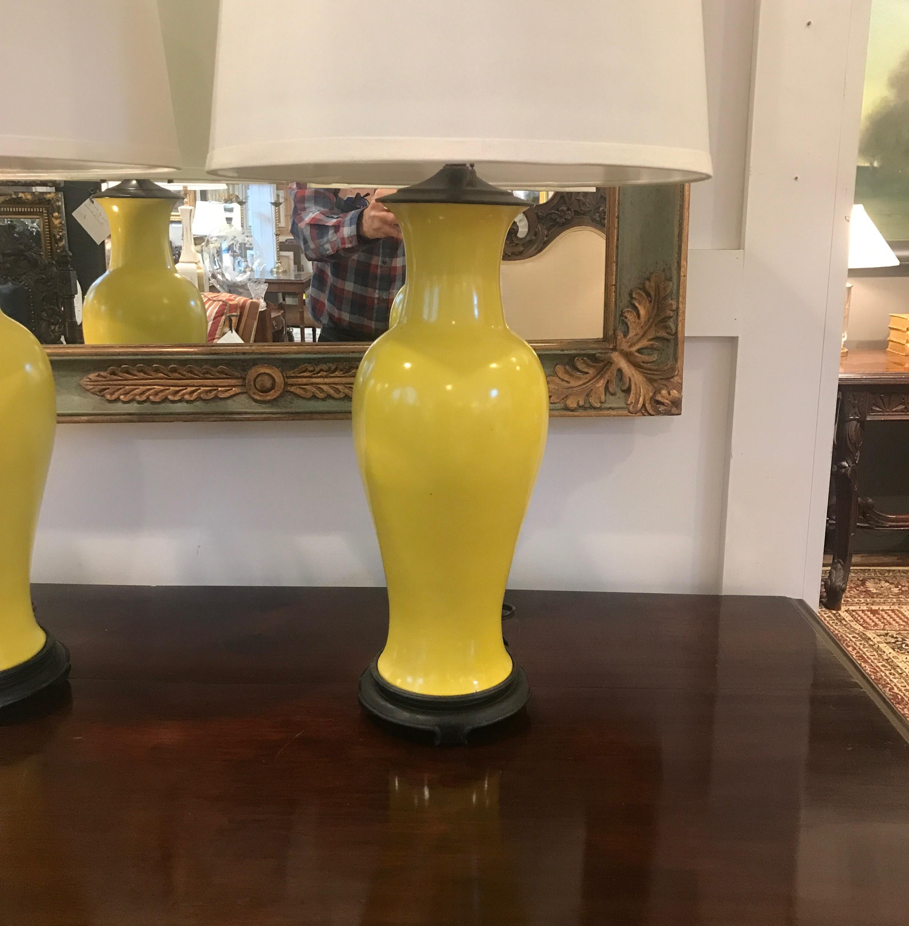Elegant and classic Chinese porcelain lamps with rosewood bases. These lamps is a vibrant Imperial yellow in a graceful urn vase shape. The shades are for photographic purposes only and not included with the lamps early 20th century, circa