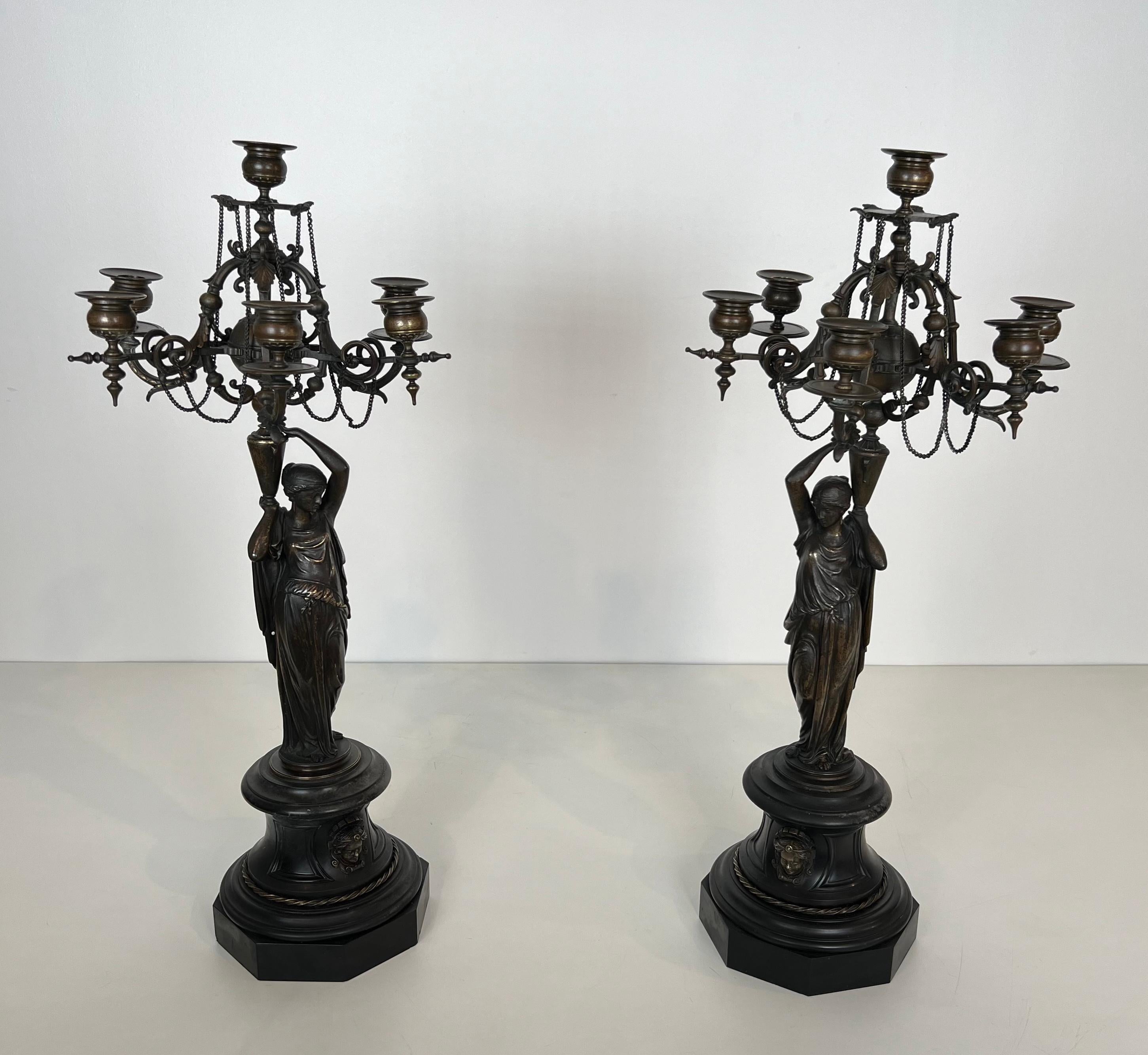 This pair of very nice and decorative tall candelabras are made of patinated bronze featuring caryatids holding 5 candlesticks on a black marble base decorated with bronze decorations. This is a French work in the style of LVE ROBERT Louis-Valentin