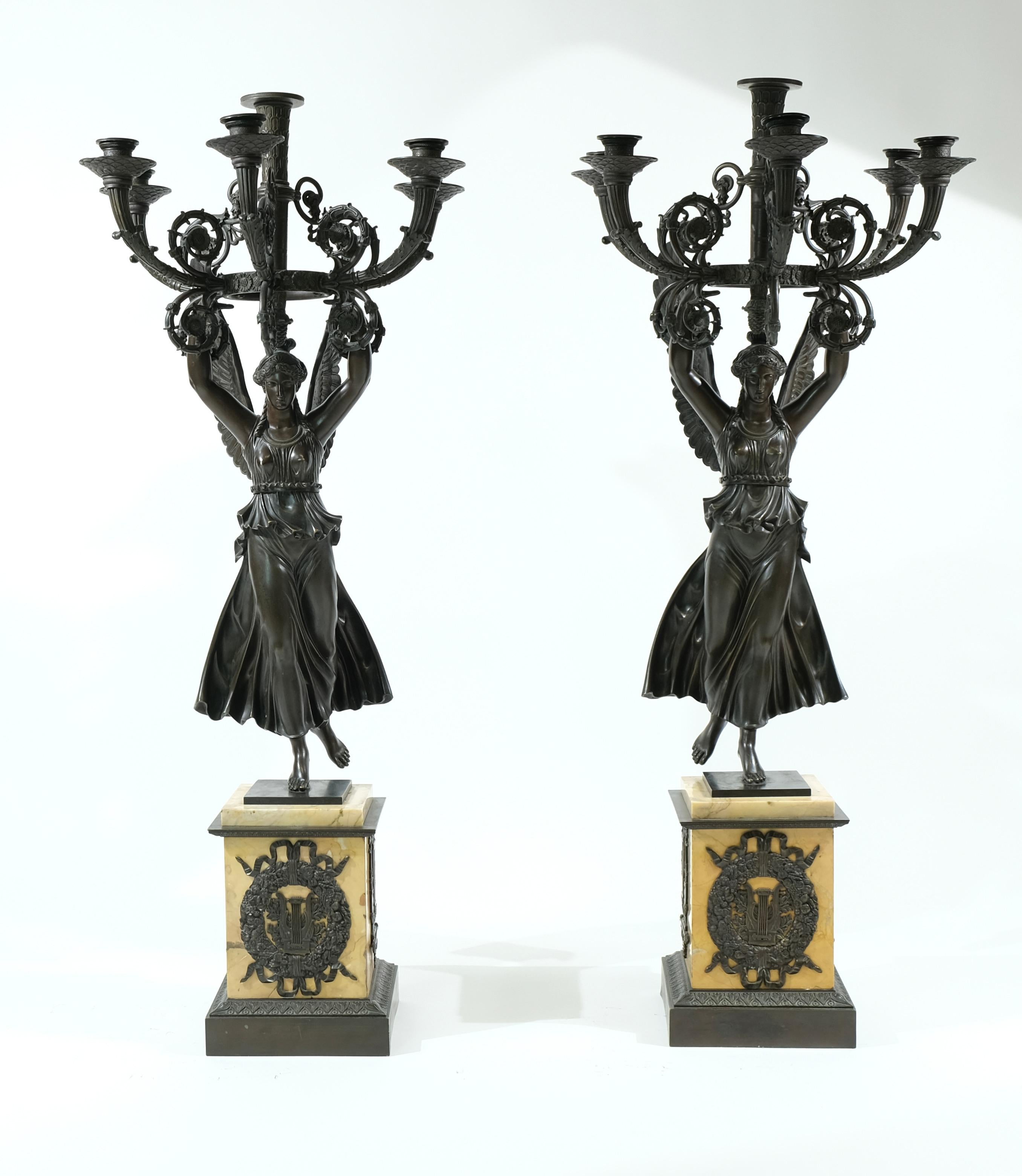 Ein Paar großer Empire-Kandelaber aus der Zeit um 1815. Die Sockel sind aus Siena-Marmor gefertigt und mit Bronze-Ornamenten versehen. Auf den Sockeln stehen die Skulpturen der Frauen des Sieges, die jeweils fünf Zweige mit Kerzenhaltern halten. Die