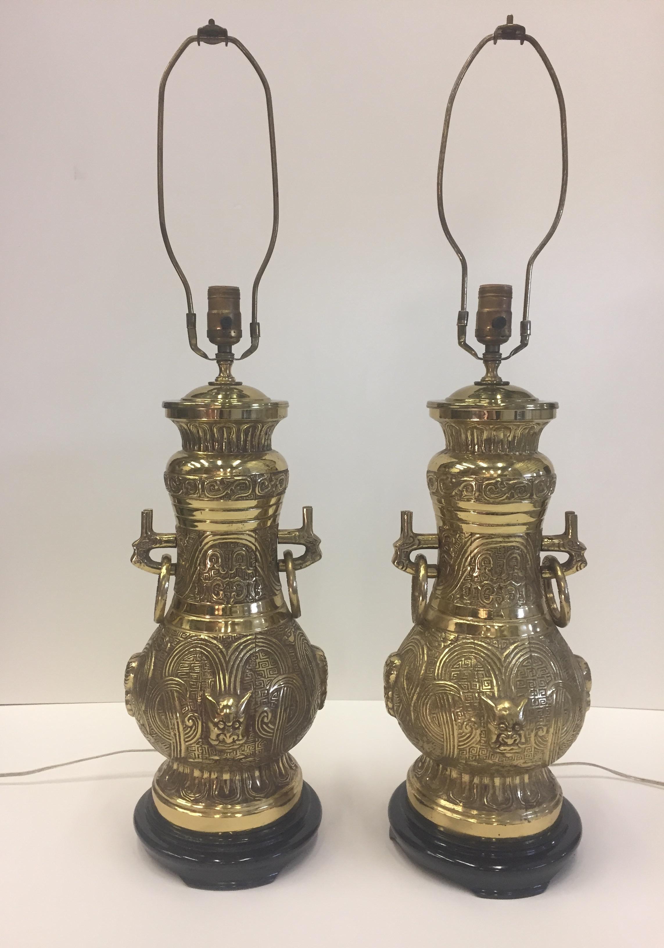 Impressively decorative brass Asian style large lamps having ebonized bases, loose rings on the sides and a glamorous face motif.
Beautiful new black square shades.
3 way bulb socket in each.