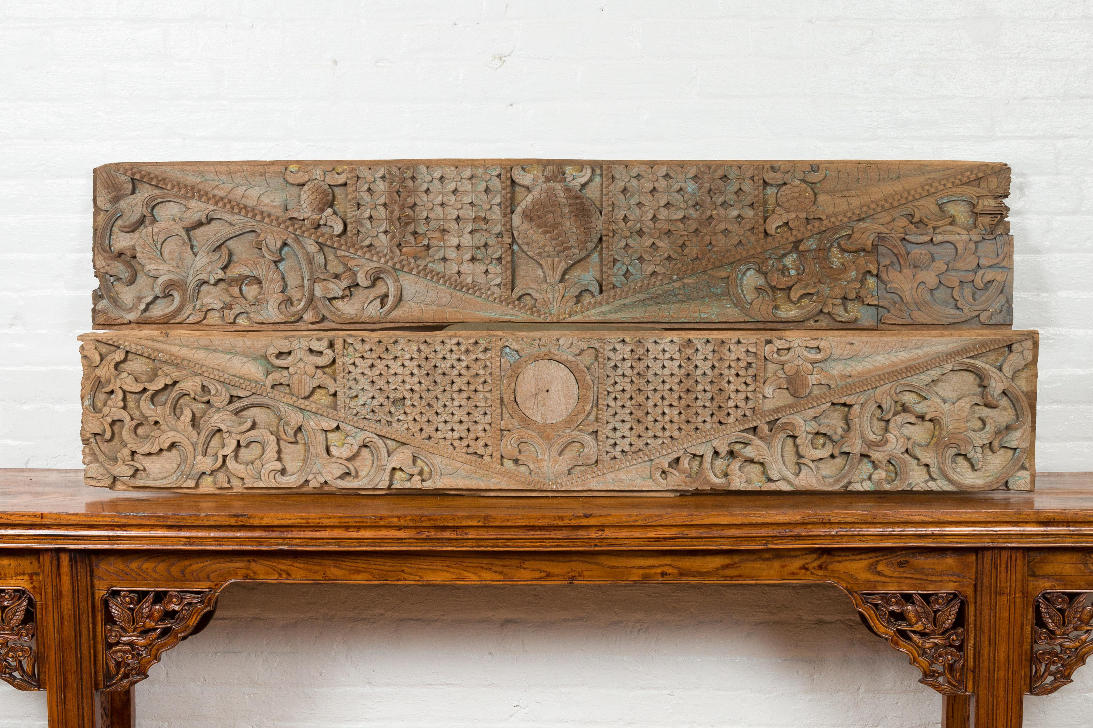 A pair of antique Indonesian carved wood overdoor panels from the 19th century, with traces of original paint. Crafted in Indonesia, each of these horizontal carved panels features geometric motifs surrounding a delicate scrolling foliage, accented