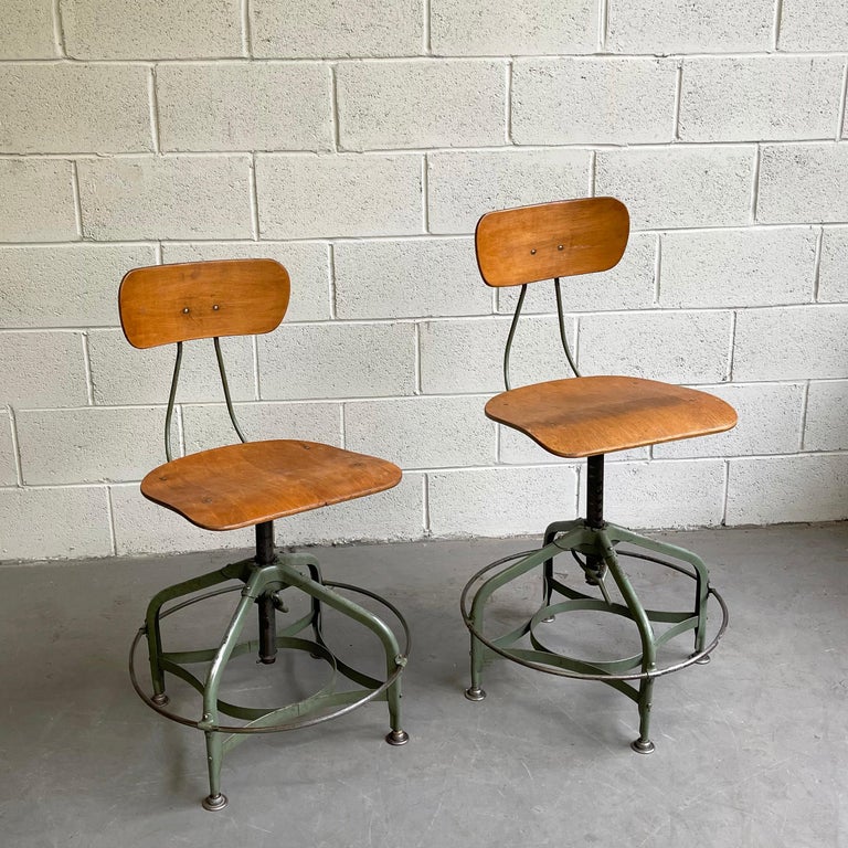 Pair of industrial, factory stools by Toledo Metal Furniture Co. feature height adjustable, painted metal, 21 inch wide ring frames with maple, potato chip seats and backs. They are height adjustable from 16.5 - 23 inches. The seats measure 16 W x
