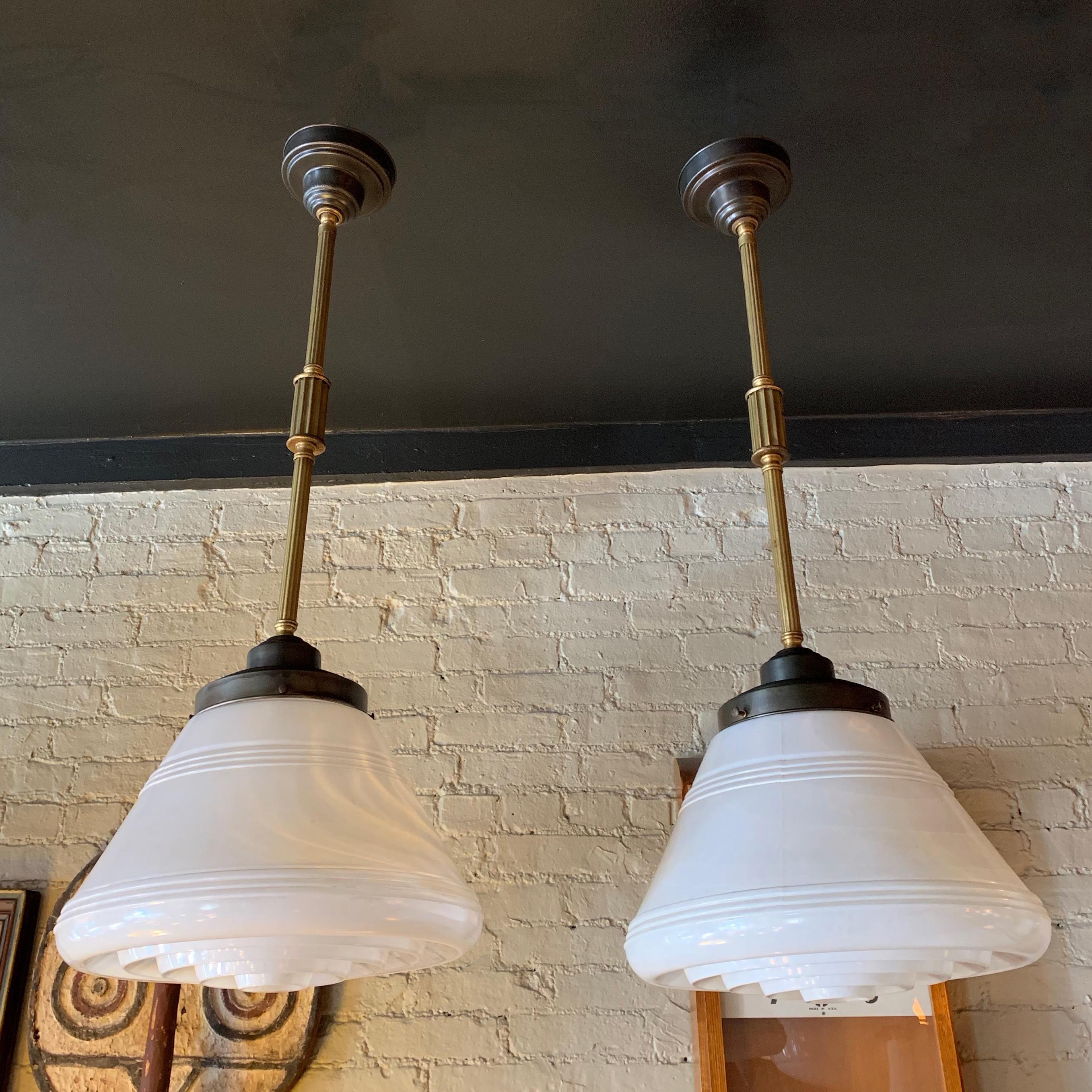 Early 20th century, industrial, art deco, pharmacy pendant light features a milk glass cone shade with clear ridged bottom attached to a two-tone brass stem with ceiling canopy that hangs 35 inches long. The pendant is newly wired to accept up to a