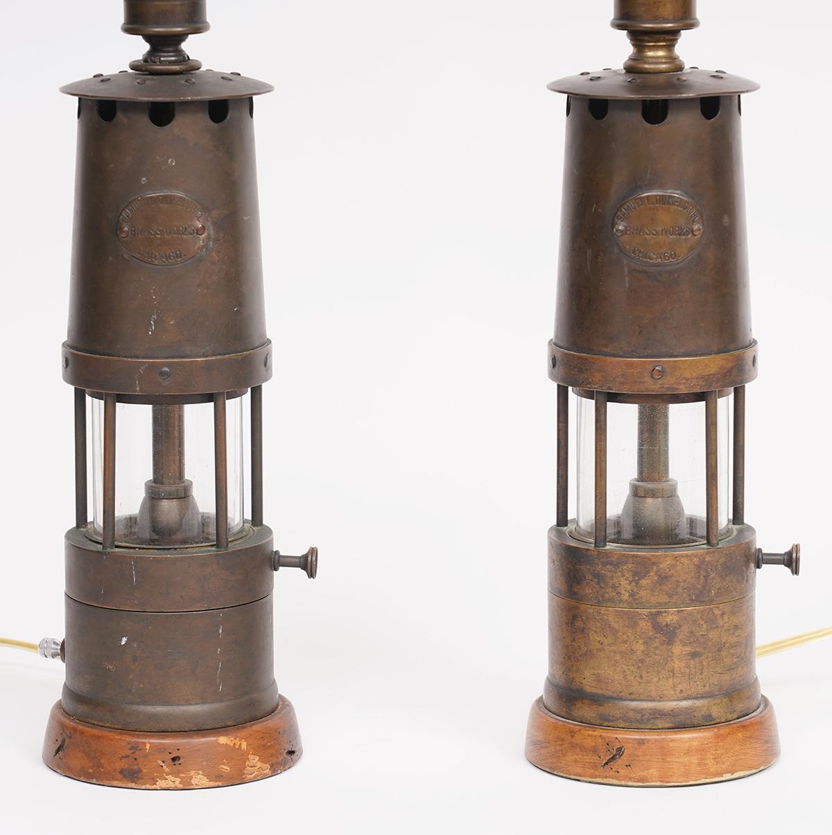 Samuel L. Dinkelspiel brass works in Chicago is known for several well crafted products including many lamps. This pair of brass and copper miner's lanterns have been converted into table lamps with wood bases and a top stems holding sockets and