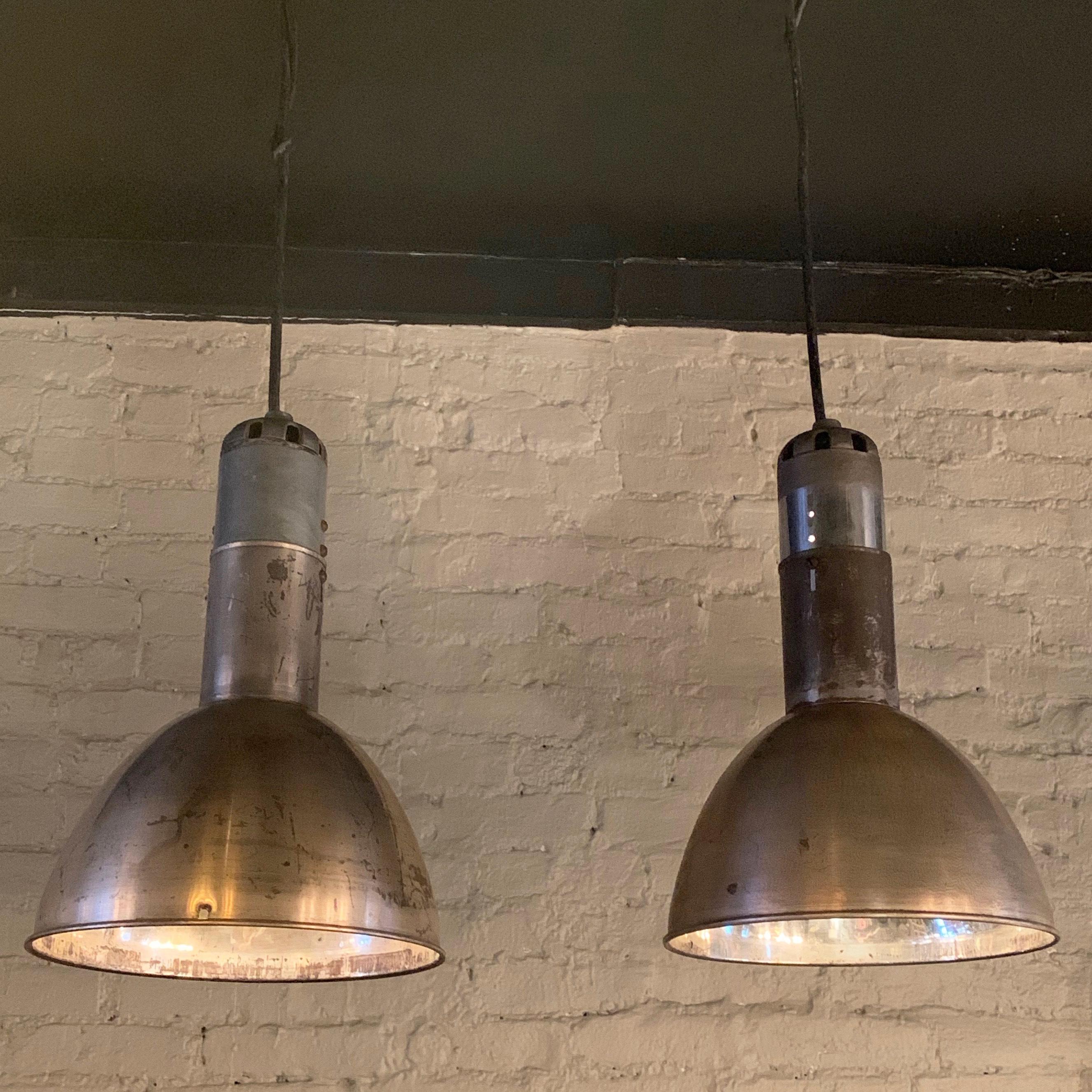 Pair of industrial, factory pendant lights feature nickel-plated steel dome shades with reflective polished nickel interiors. The pendants are newly wired with 40 inches of thick black rubber cord to accept up to 200 watt bulbs.