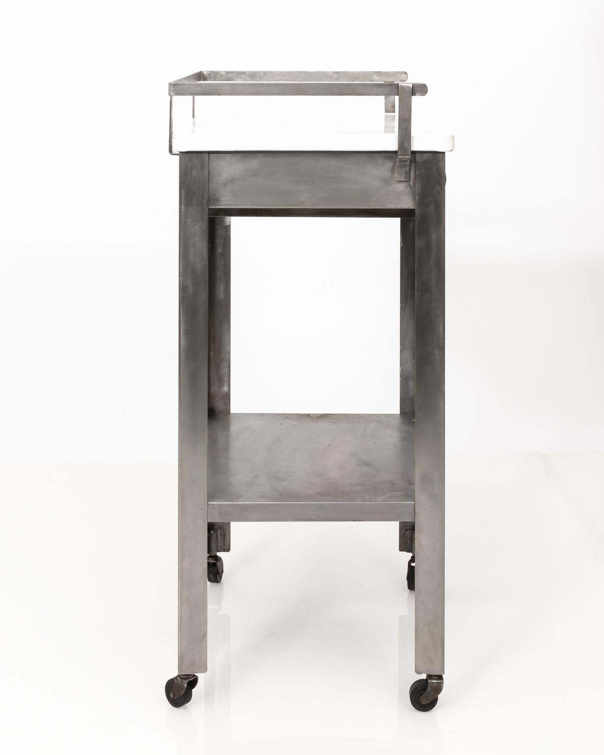 Pair of Industrial brushed steel stands with one drawer and bottom shelf on wheels, circa early 20th century. The enamel top is removable.
 