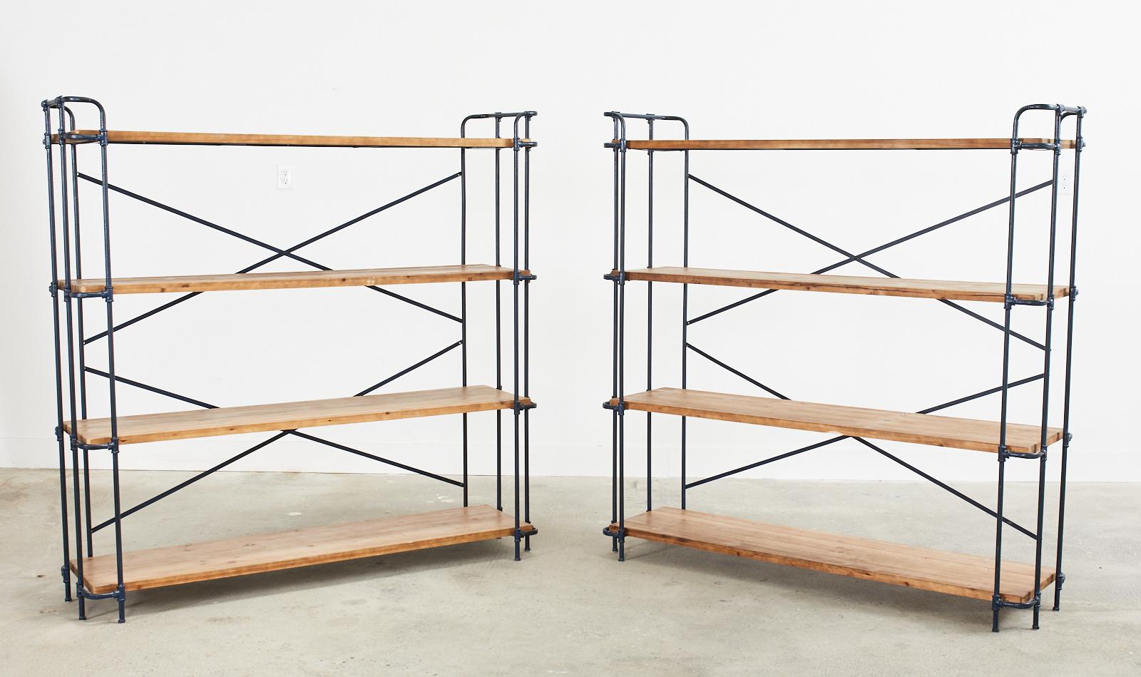 Large pair of handsome metal and pine bookshelves or bookcases made in the industrial style. The frames are constructed from vintage style metal pipes and pipe joints having an intentionally aged painted patina. The top shelf has a galleried edge