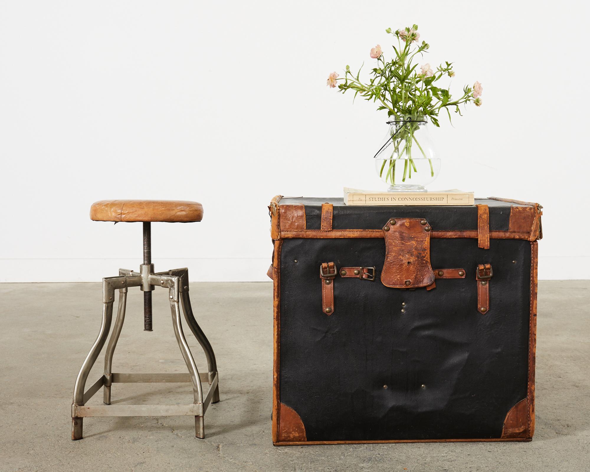 Unique pair of industrial style machinist swivel stools crafted from steel with a polished finish. The stools are height adjustable from 20 inches to 28 inches high. The 12 inch round seats have an aged leather seat cover. The steel frames have an