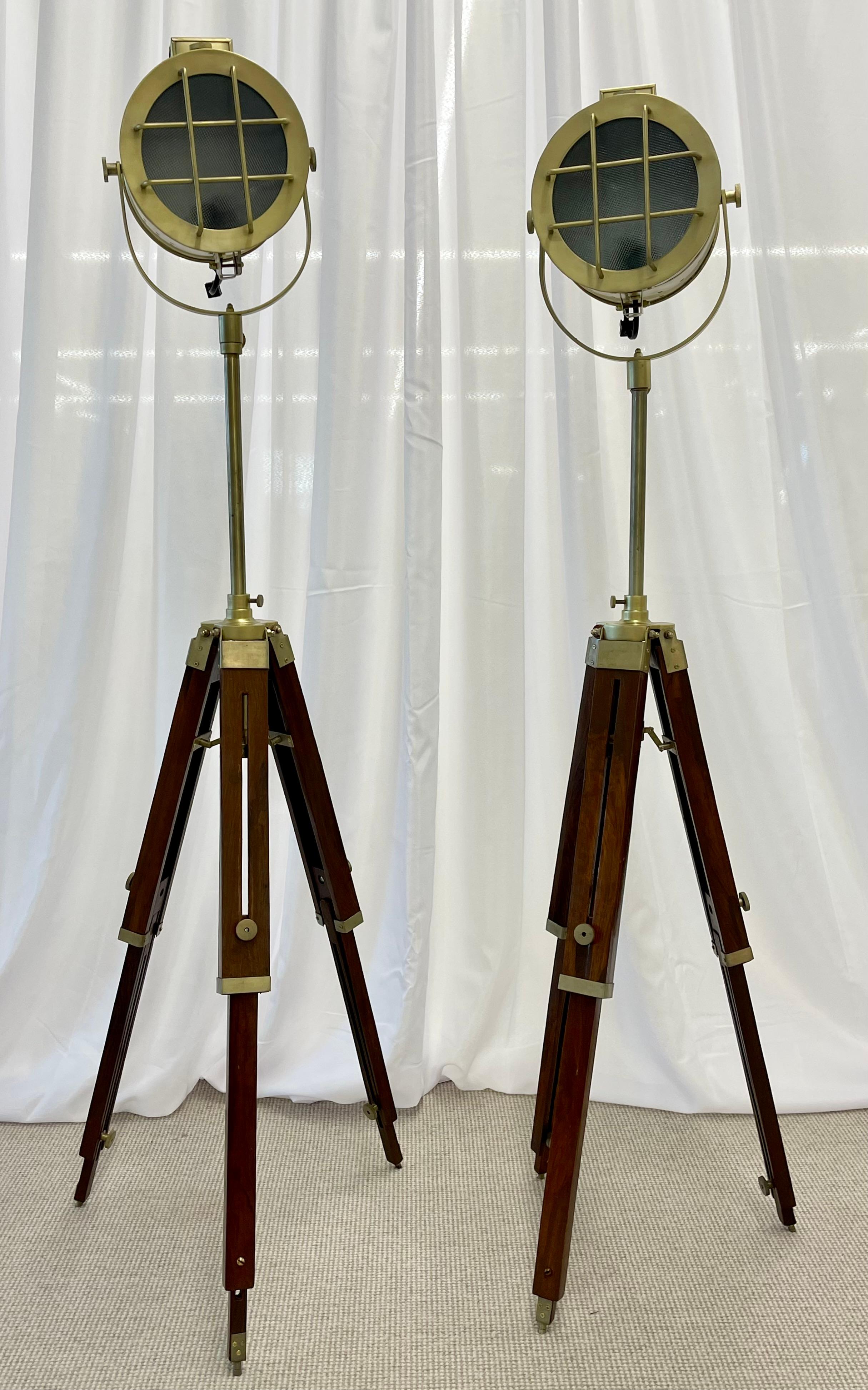 Pair of Industrial style search lights, the brass adjustable search lights supported on a wooden tripod base. Height is adjustable on base and on top of base.

The light itself measures 7.5