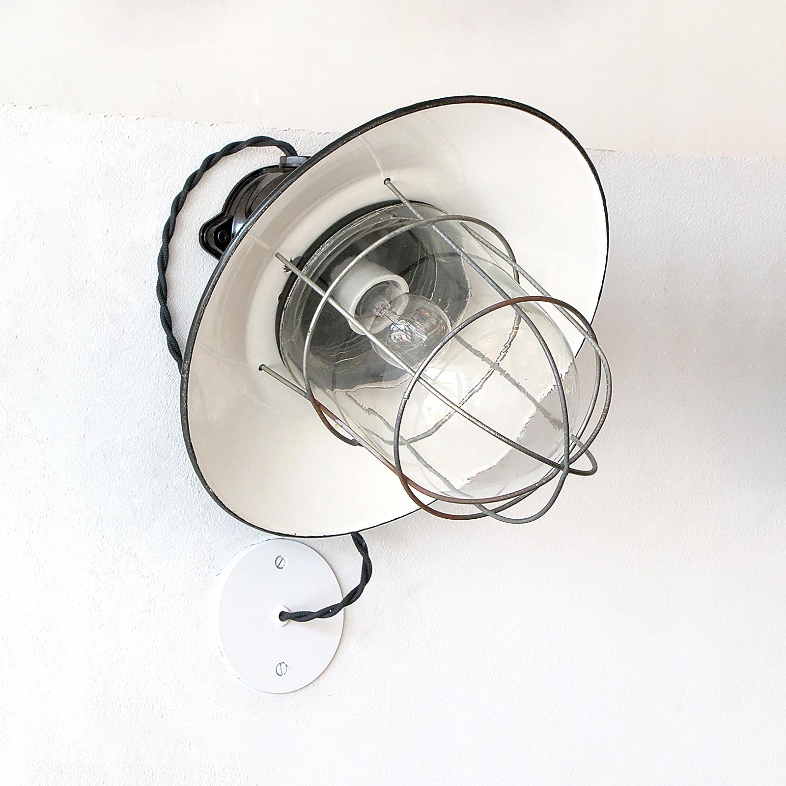 Coppia di applique industriali tedesche da interno/esterno con alloggiamenti in bachelite, paralumi in metallo smaltato e gabbie metalliche che avvolgono cupole in vetro, attualmente cablate con coperture esterne j-box, cablate per gli standard USA,