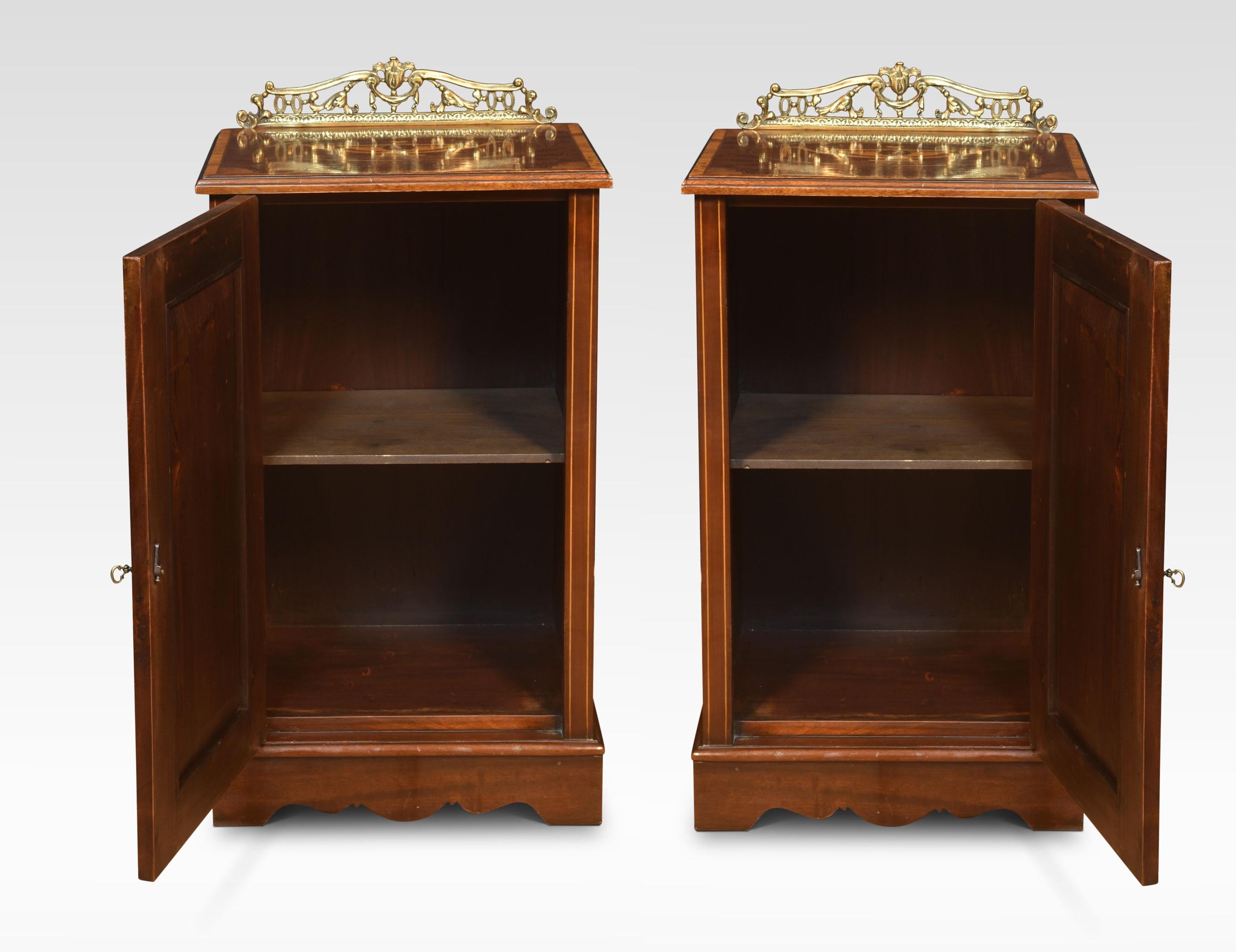 Pair of bedside cabinets, each having raised brass pierced gallery, above inlaid crossbanded tops. To the large panelled doors with marquetry panels having scrolling floral and Urn decoration. The door opens to reveal a large storage area and a