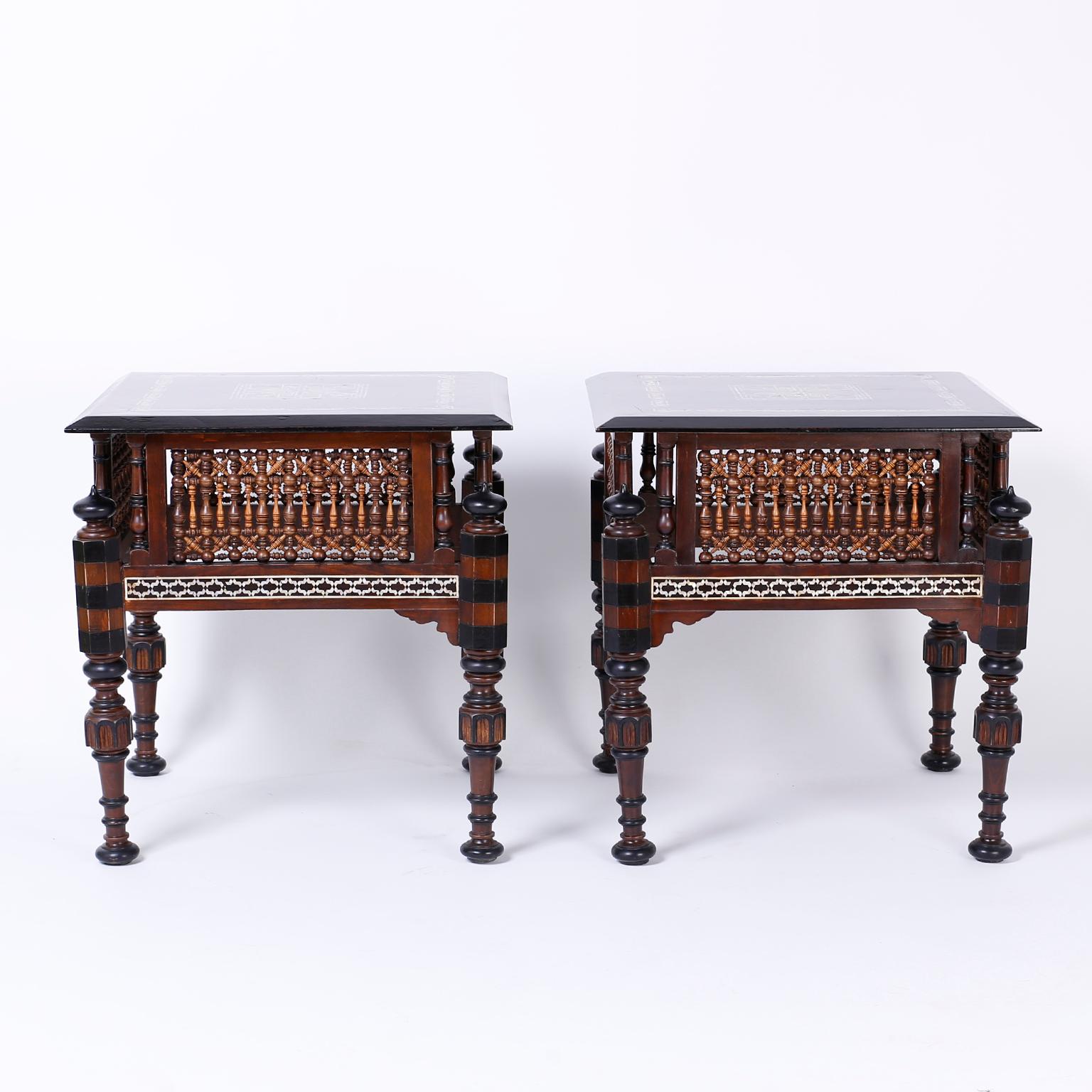 Lofty pair of Syrian side or end tables crafted in exotic hard woods with inlaid mother of pearl and tortoiseshell geometric designs. The bases have an architecturally intriguing Moorish form with stick and ball panels and turned legs with ebonized
