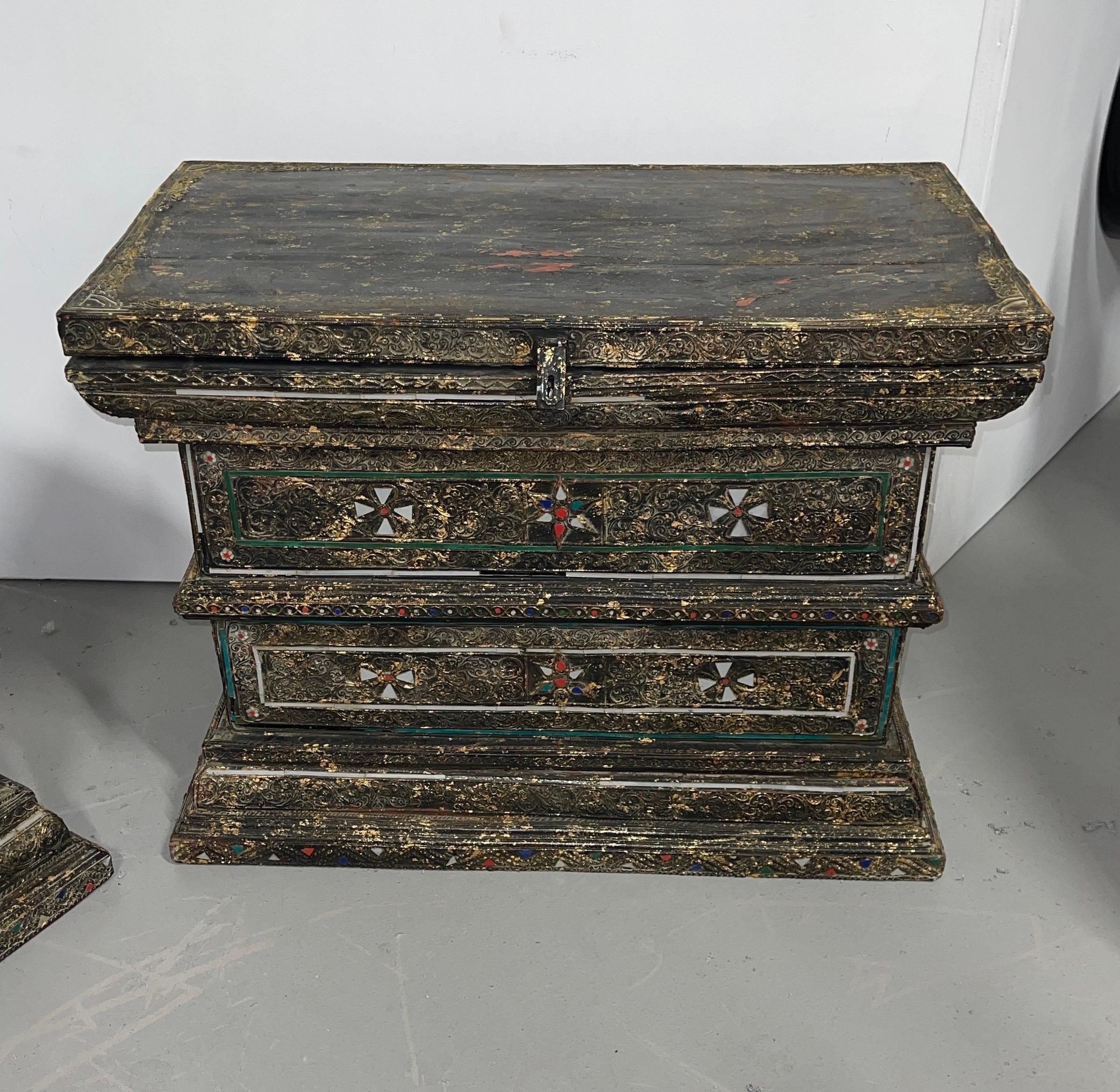 An unusual pair of inlaid dowry or wedding chests. Beautiful inlay of different color glass patterns and carved areas. The entire surface has been painted then has gold leaf splotches applied. They have Maltese type crosses and greenish glass border