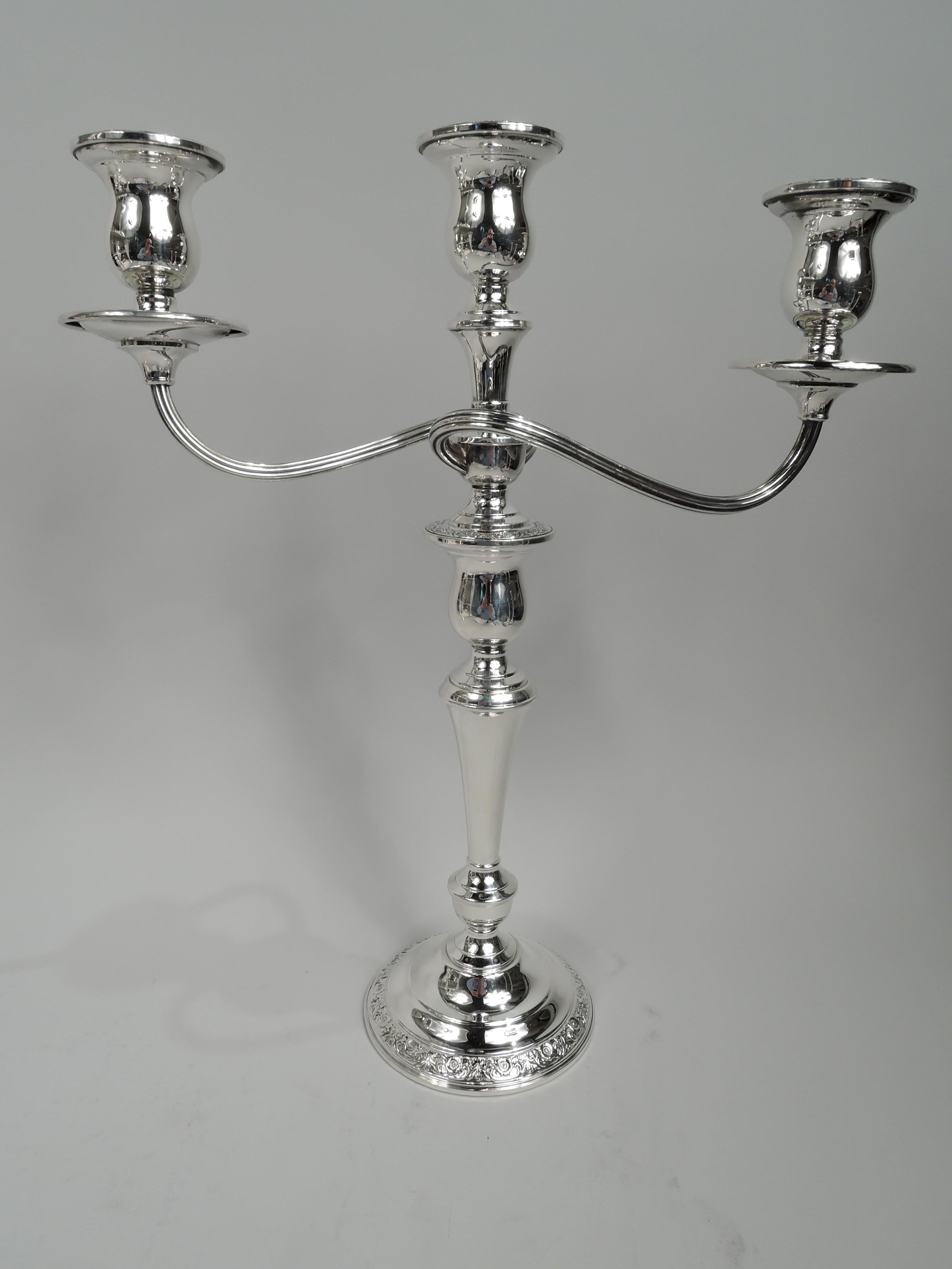 Pair of Prelude sterling silver 3-light candelabra. Made by International in Meriden, Conn. Each: Central socket and 2 wraparound reeded arms, each terminating in single socket. Tapering shaft on vasiform base mounted to stepped and domed foot.