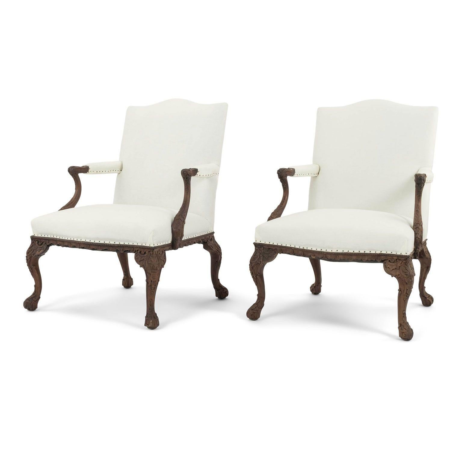 Pair of intricately hand-carved rococo style fauteuils dating to the 19th century. French armchairs hand-carved in walnut and newly upholstered in white muslin. Armchairs sold together and priced $7,800 for the pair.

Note: Regional differences in