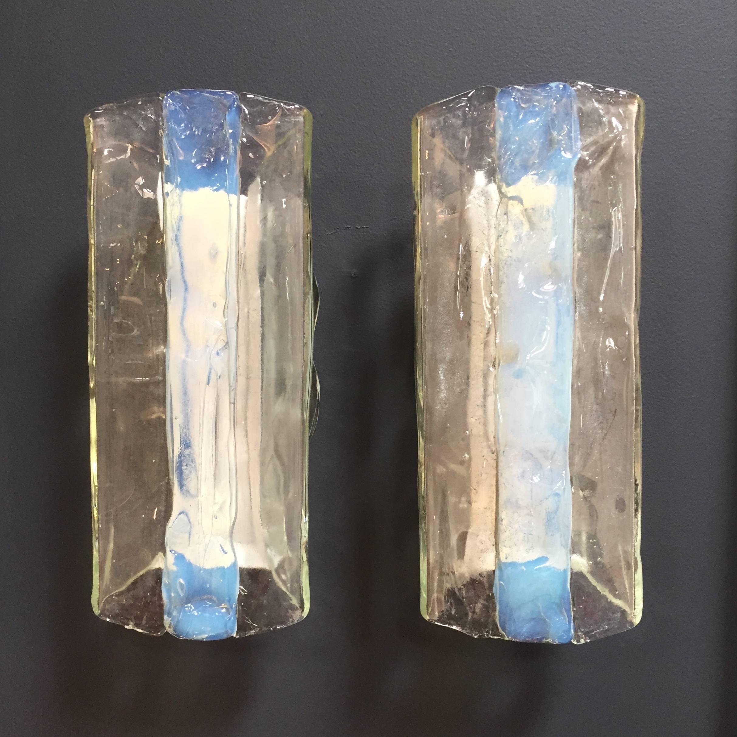 A gorgeous pair of Mid-Century Modernist sconces, both consisting of a folded iridescent handblown iridescent and clear Murano glass section, by Mazzega. White enameled back plates each fitted with two candelabra sockets each supporting up to 60W