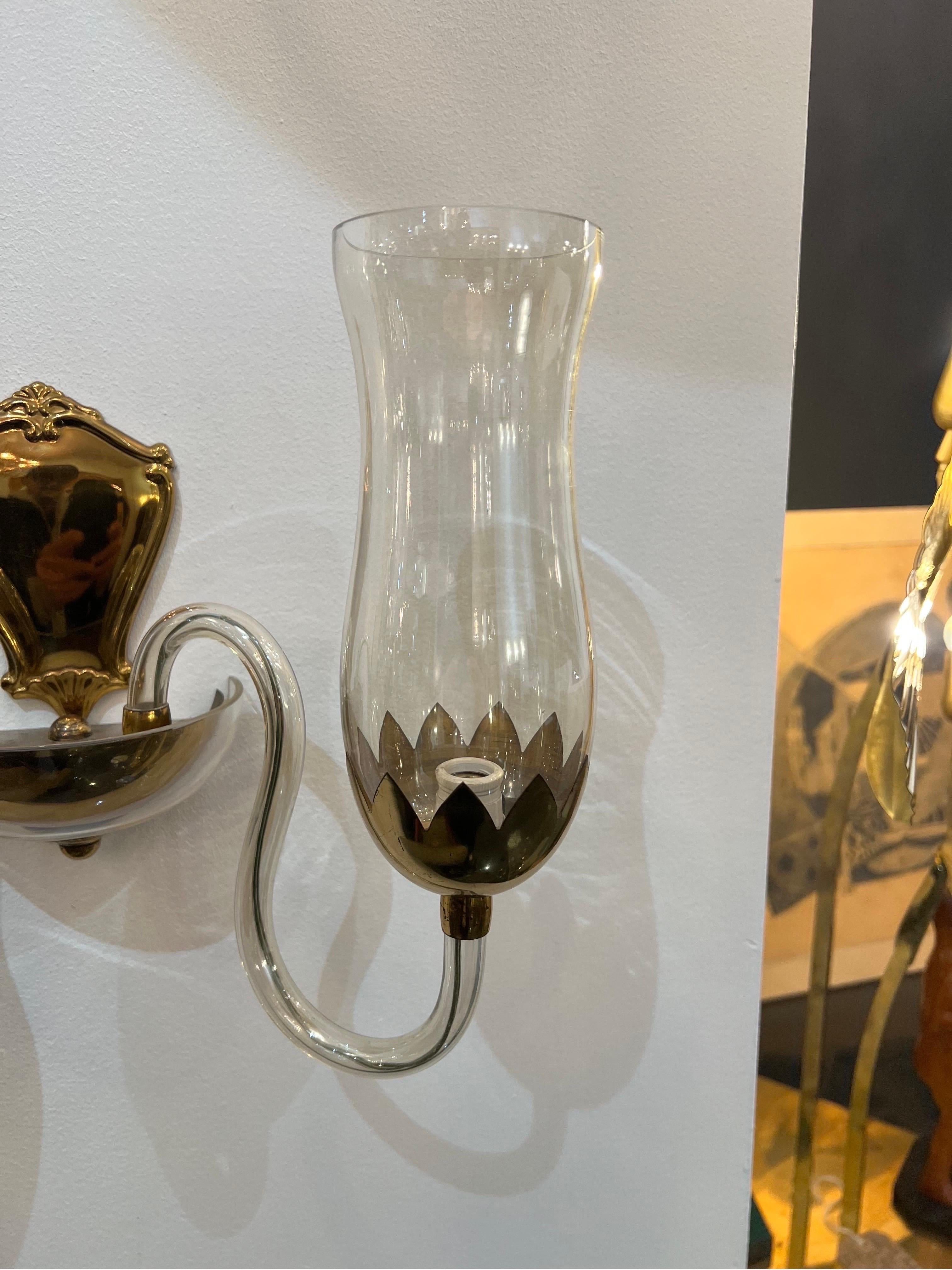 Stunning pair Murano glass wall sconces consisting of two delicately curved arms in gold/amber glass each holding a lantern shaped glass lamp holders with brass detailing. Rare pieces made entirely from hand blown glass supported by elegant brass