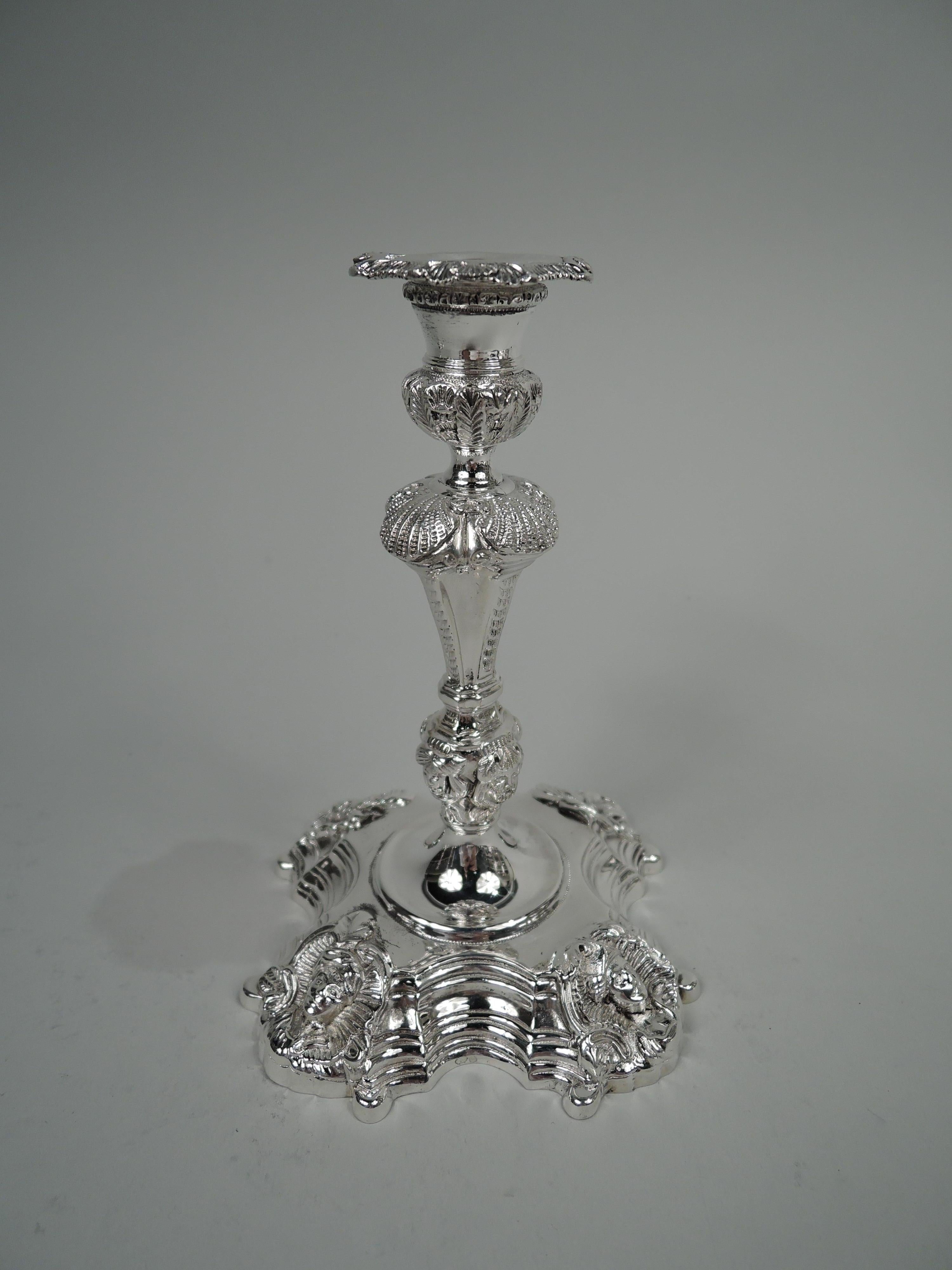 Pair of Irish Georgian cast sterling silver candlesticks. Traditional form of fluted baluster shaft on stepped serpentine foot; socket bellied with detachable cruciform bobeche. Ornament includes scallop shells and a range of human heads from