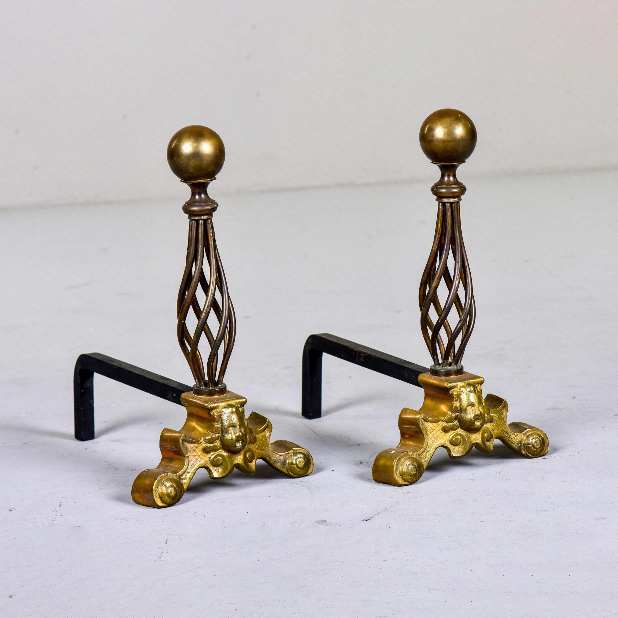 Found in France, this pair of circa 1940s andirons feature an iron base and gilded cherubs topped with an open work spiral of twisted brass strands and large round brass finials. Unknown maker. Sold and priced as a pair.