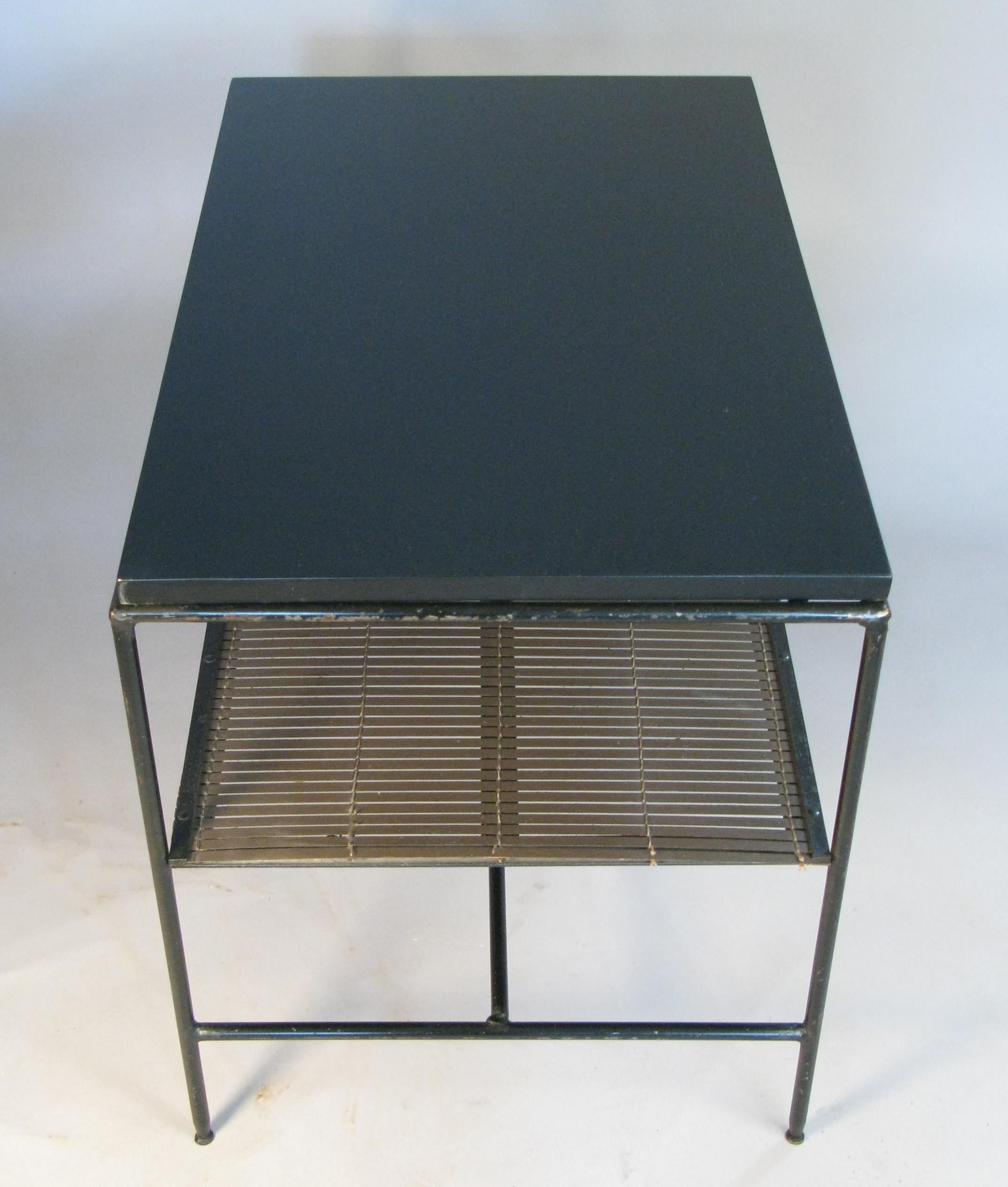 A pair of 1950s tables or nightstands by Paul McCobb, from the Planner Group series for Winchendon, with wrought iron frames, ebonized birch tops, and woven rattan mat lower shelves in dark brown. Tops and rattan shelves have been refinished. Frames