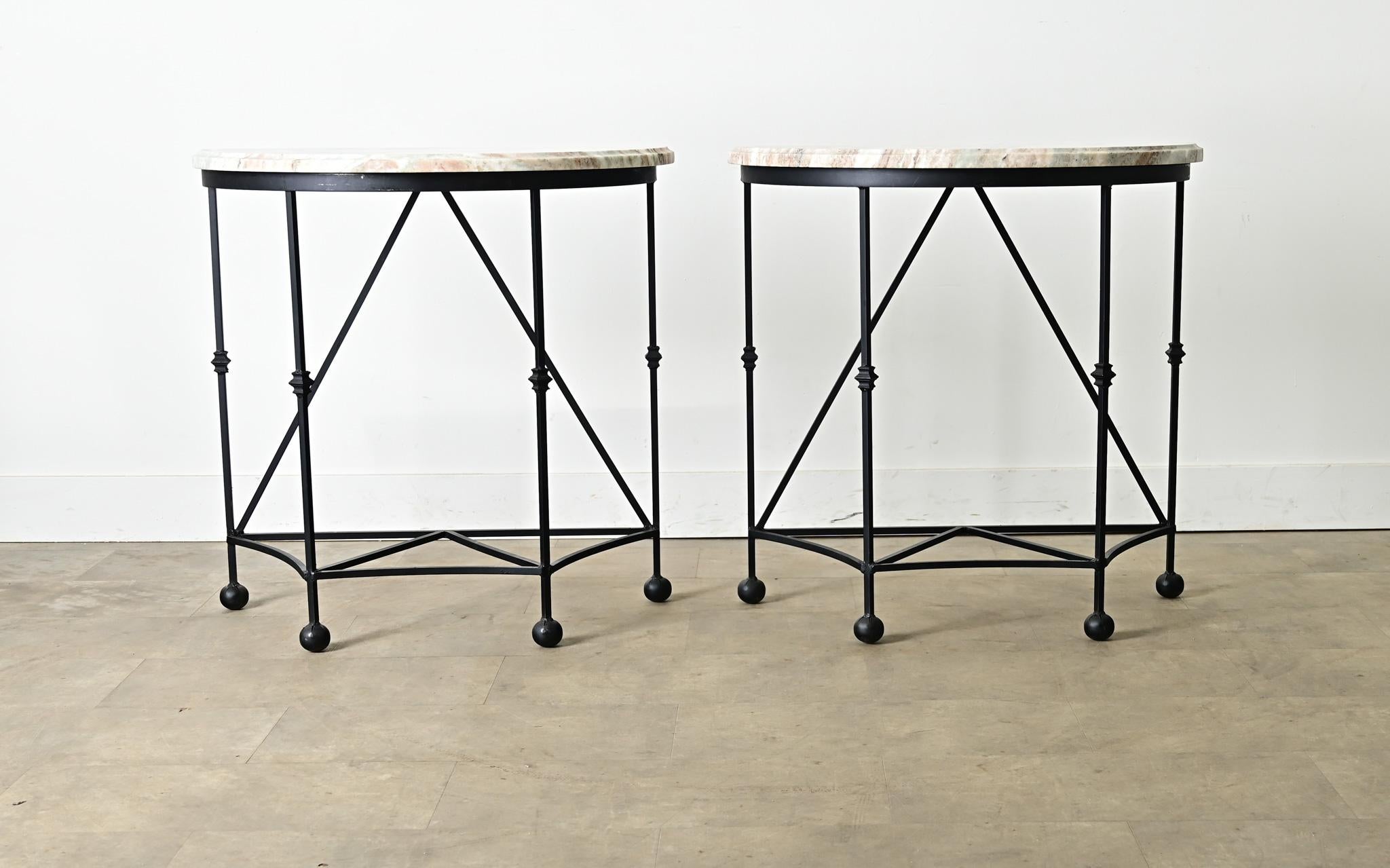 A unique pair of iron and marble demilune console tables, made more recently but with timeless French styling to suit any interior or patio. The half-round marble tops are new, streaked with pastel veining of green and taupe subtly merging with the