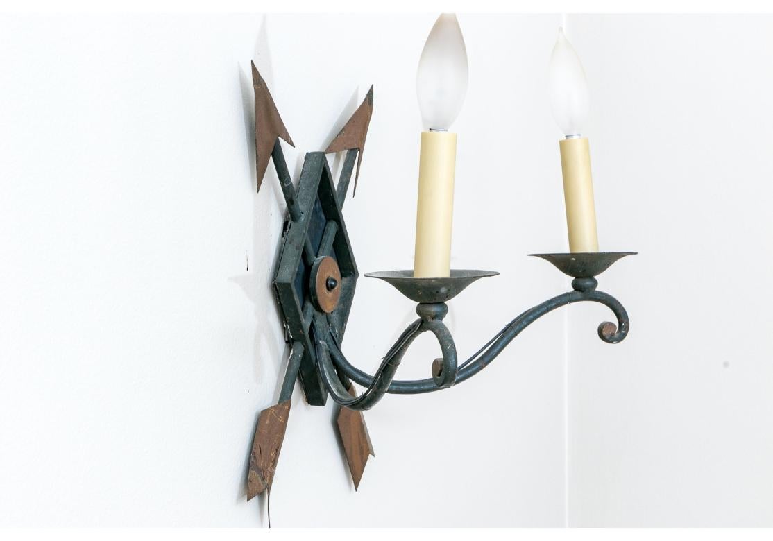 With crossed arrows through the sconces diamond form wall mount. Extending forward are the pair of scrolled arms with wax drip plates supporting the candle sheaths with bulb nozzles.

Dimensions: 15