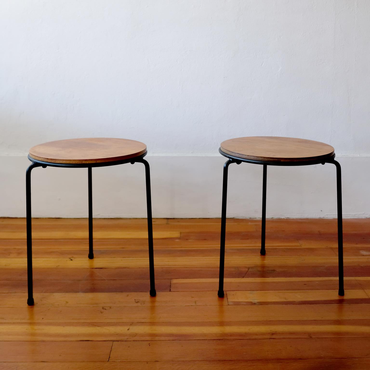 A pair of tripod iron and walnut stackable tables or stools. Floating walnut top and clever rubber rings to prevent damage while stacking, American, 1950s.