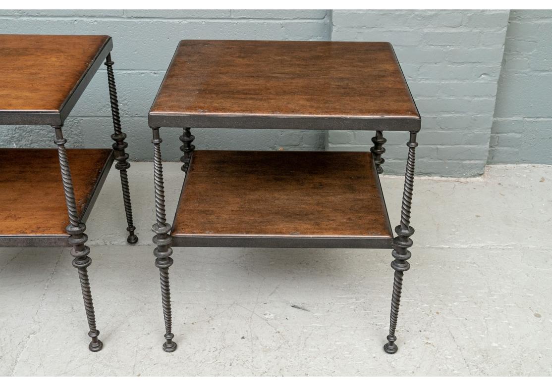 A Pair of very well-made and solid feeling tables by Paul Ferrante. Interesting black swirled iron legs with disk details above and below the lower tier. With inset brown wood top and lower tier. 
Measures: H. 29