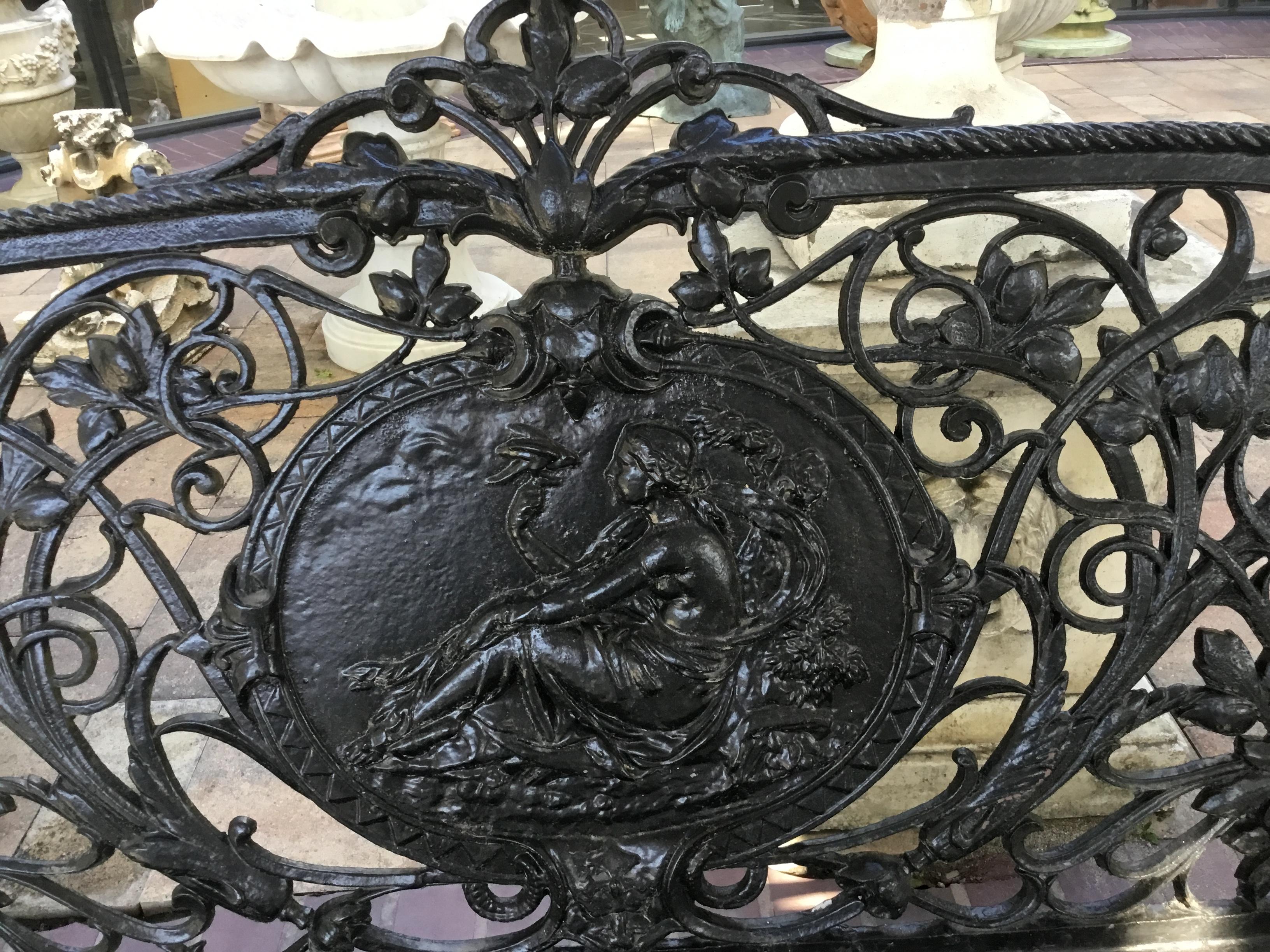 The medallion backs each decorated with a seated classical maiden, a bird perched on her finger,
Against a ground pierced vines and scrollwork, with slatted iron seats, the Sabre-form legs with hoof
Feet. Birds on each side of the medallion