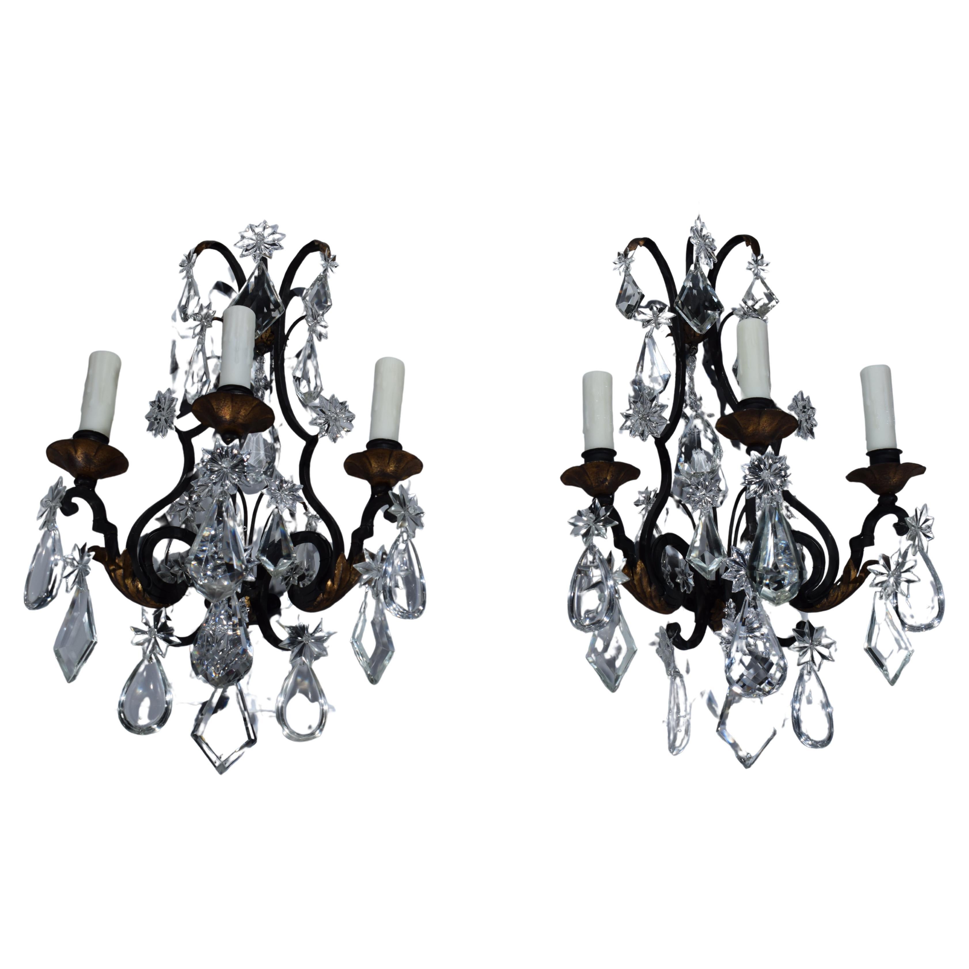 Paire d'appliques murales en fer, ornées de feuilles d'acanthe et de barbillons dorés. Pendentifs en cristal, dans le goût Louis XV. France, vers 1920. 3 lampes chacune.
Dimensions : Hauteur 22