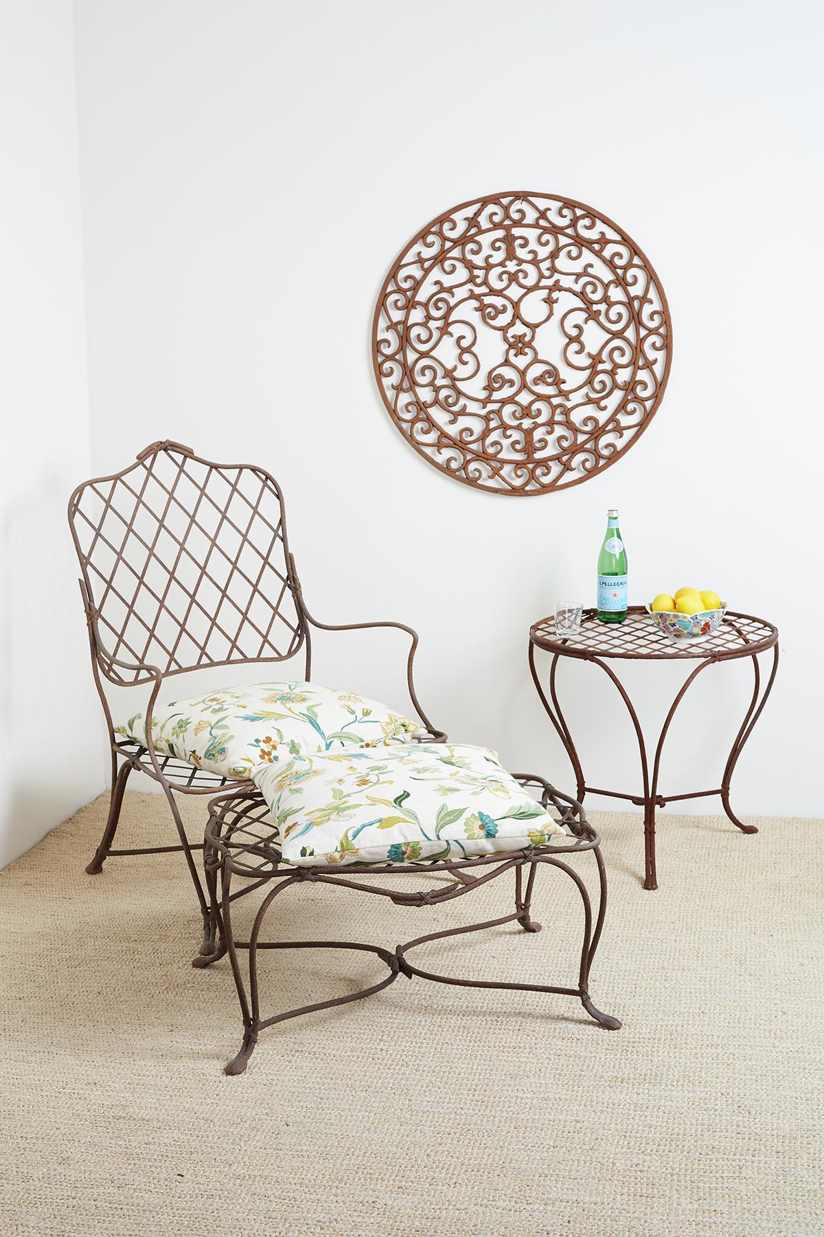 Impressive pair of iron garden or patio chairs with ottoman. Featuring a delicate faux-bois finish on the thin twig frames decorated with neoclassical swag ribbon on the joints. The graceful frames have a peaked lattice back and seat shown with