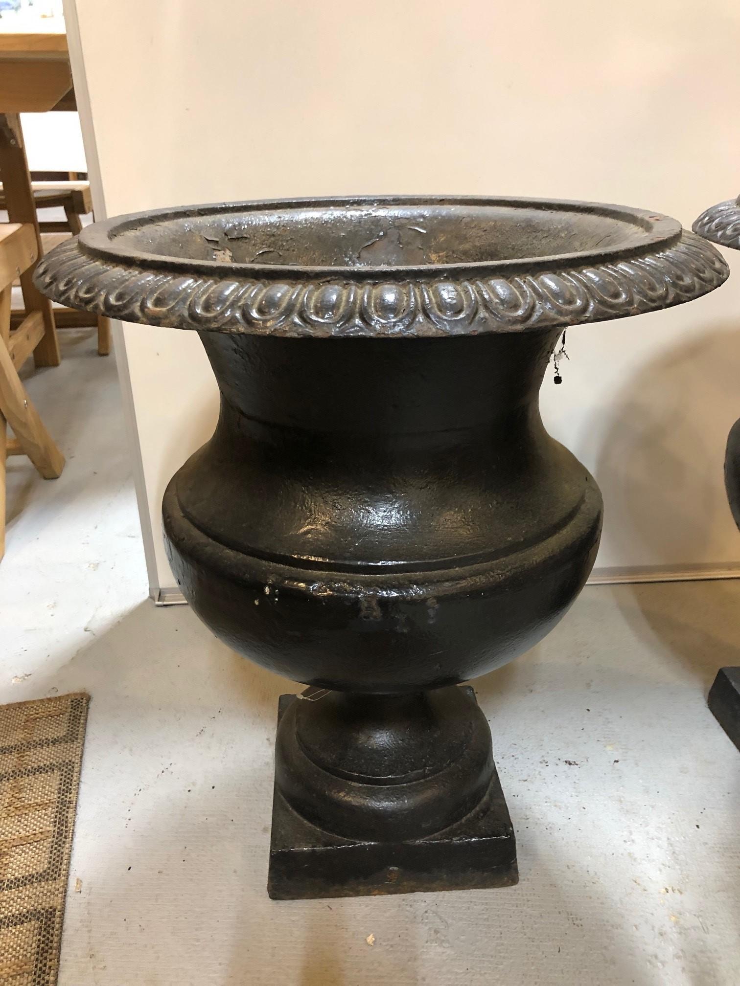 Vintage pair of Iron Garden Urns with a square pedestal base. This pair would look fantastic on either side of a doorway or in a garden .The urns are in very good condition with some loss of finish and areas of rust. Measures: Height 22