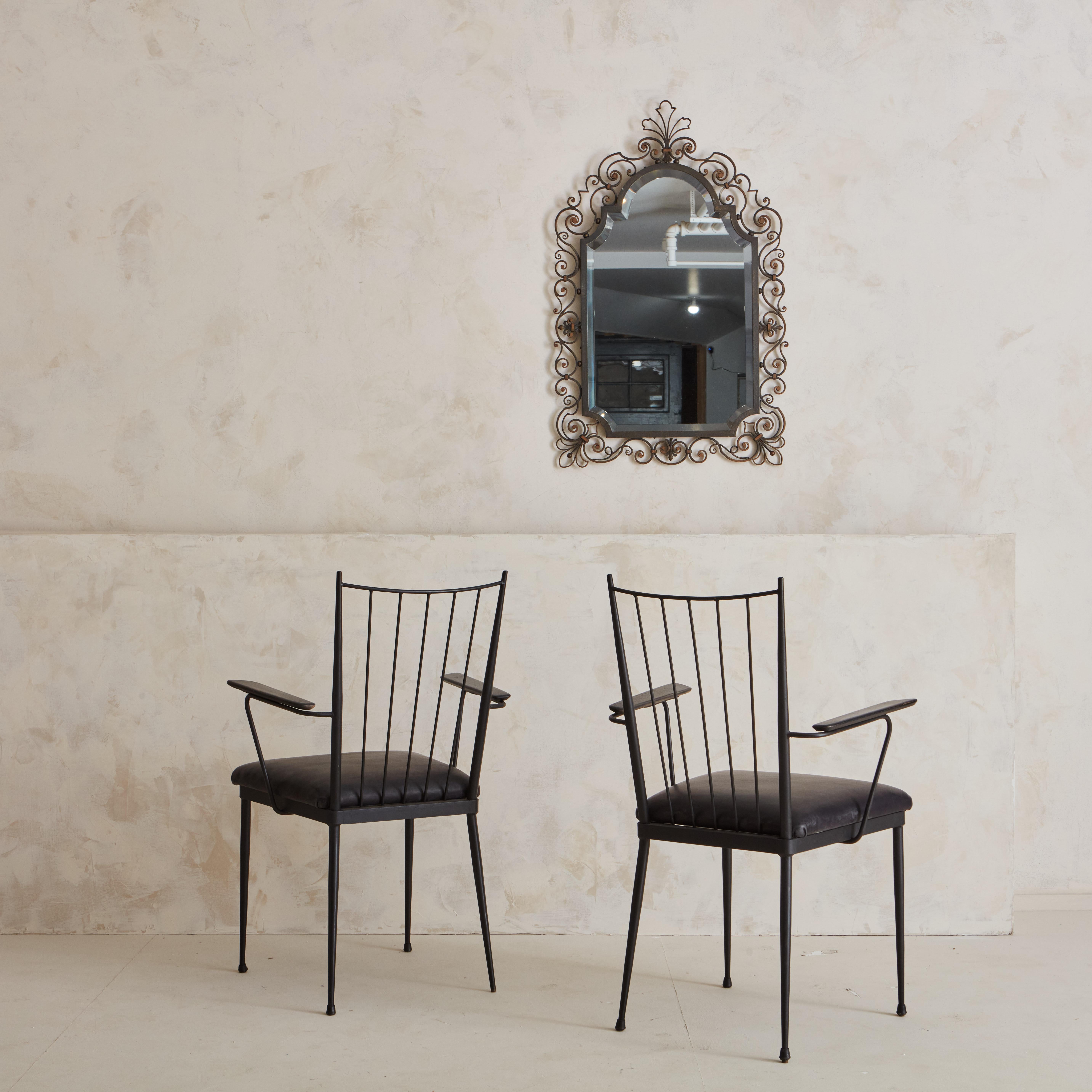 A pair of Iron Chairs by Colette Gueden, circa 1950s, featuring a leather seat and wooden armrests. Colette Gueden is a French designer, most known for her work produced by the design studio Primavera. Sourced in Southern France.